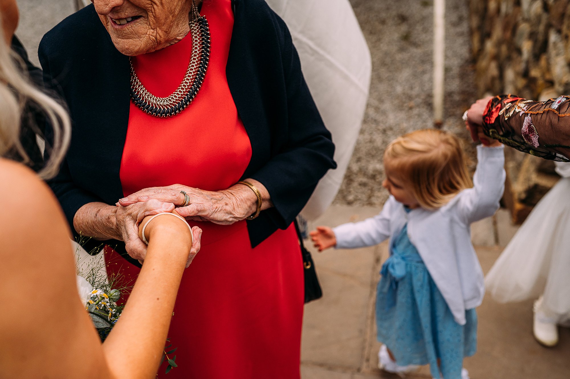  Grandma holding ladies hand with small girl holding someones hand at the side. 
