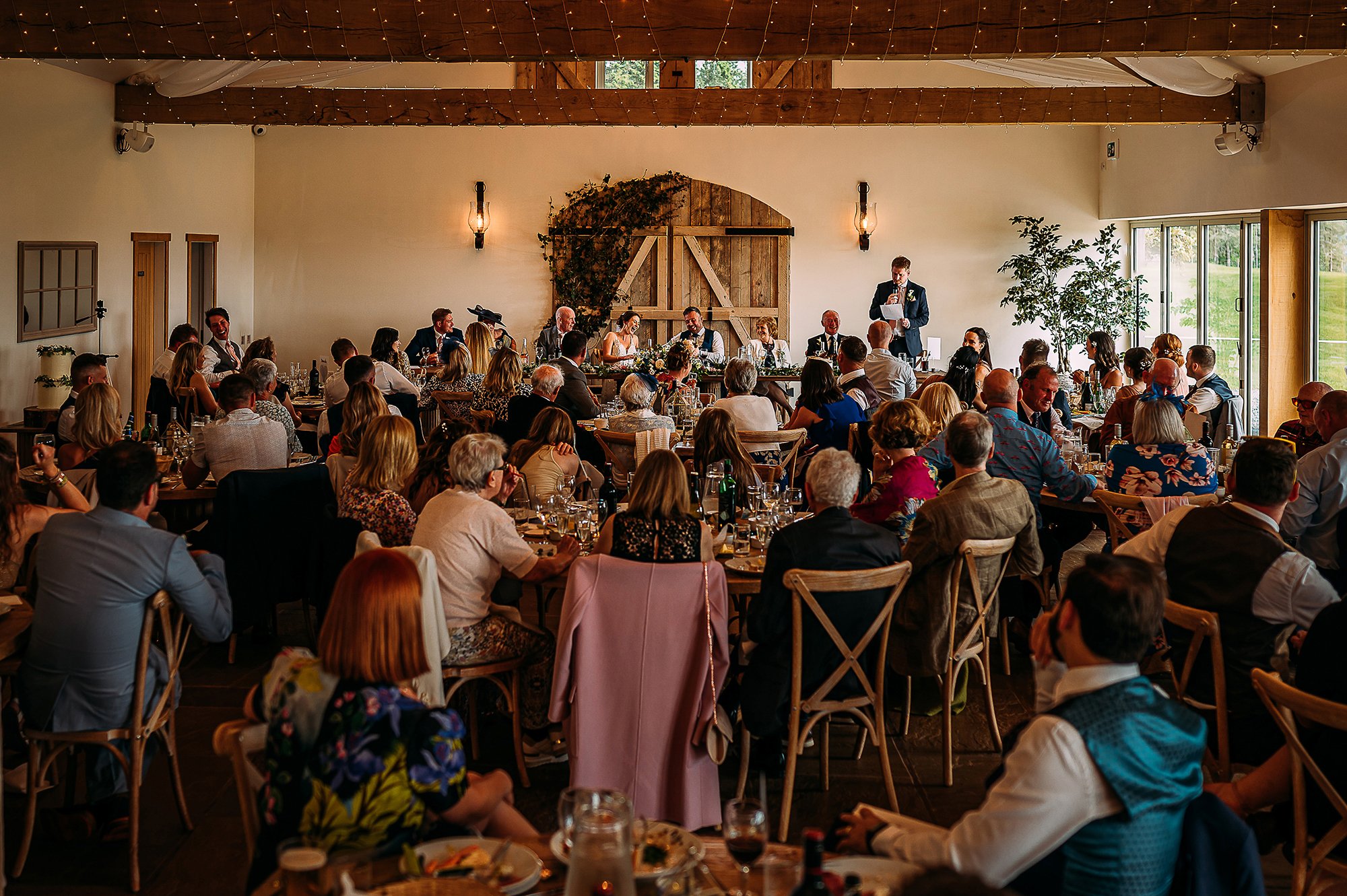  Wide shot of a full room during the best man speech. 