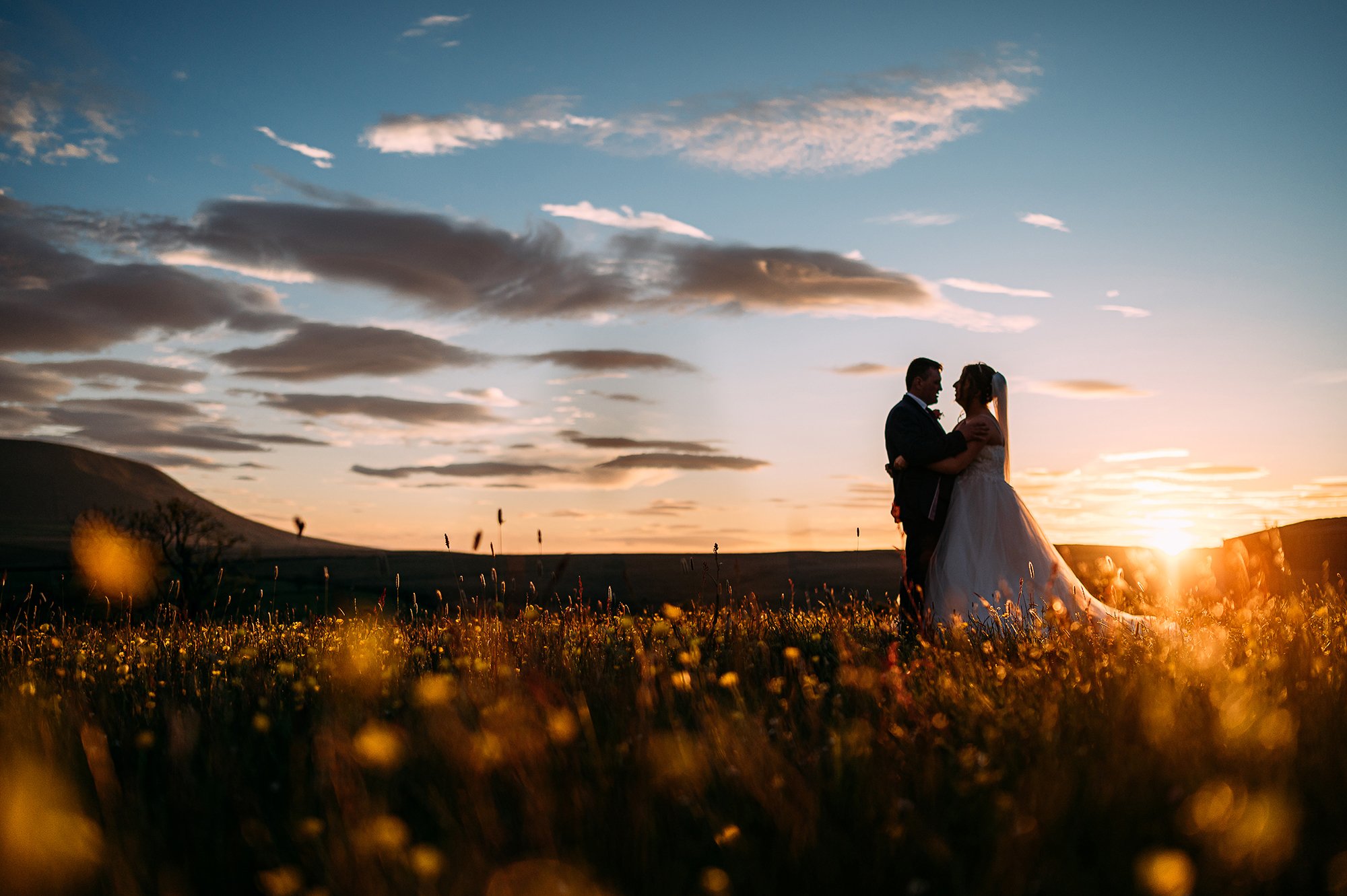  Silhouette of couple at sunset in front of Pendle hill. 