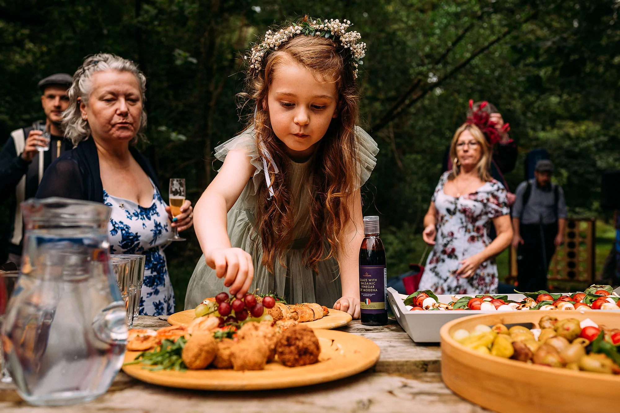 A girl climbing on the table to pinch food.