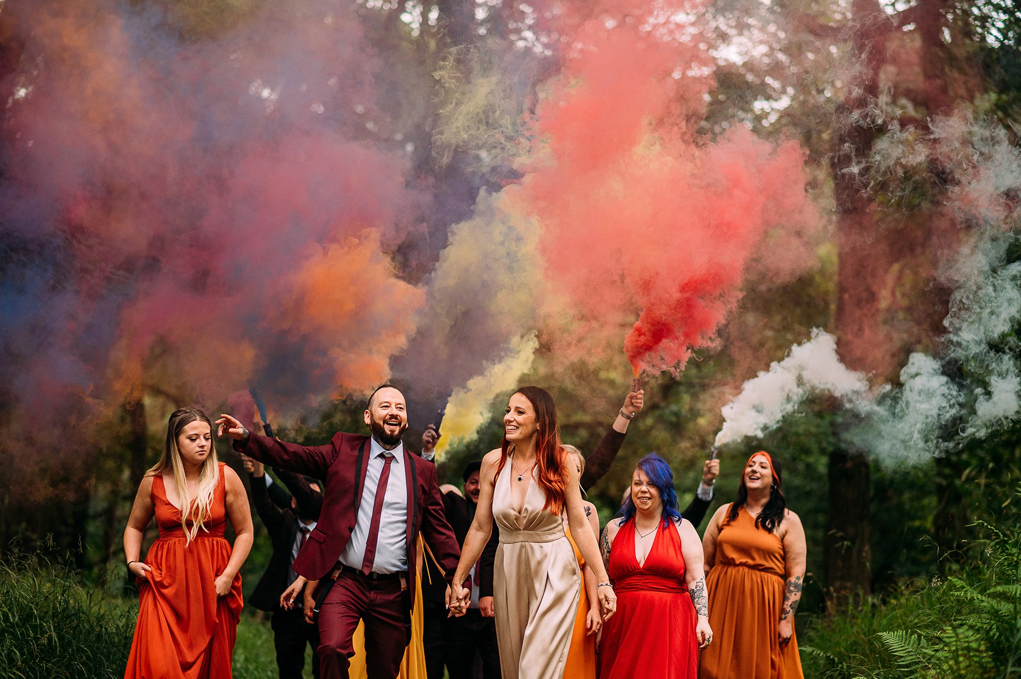  Wedding party walking through the woods with smoke grenades. 