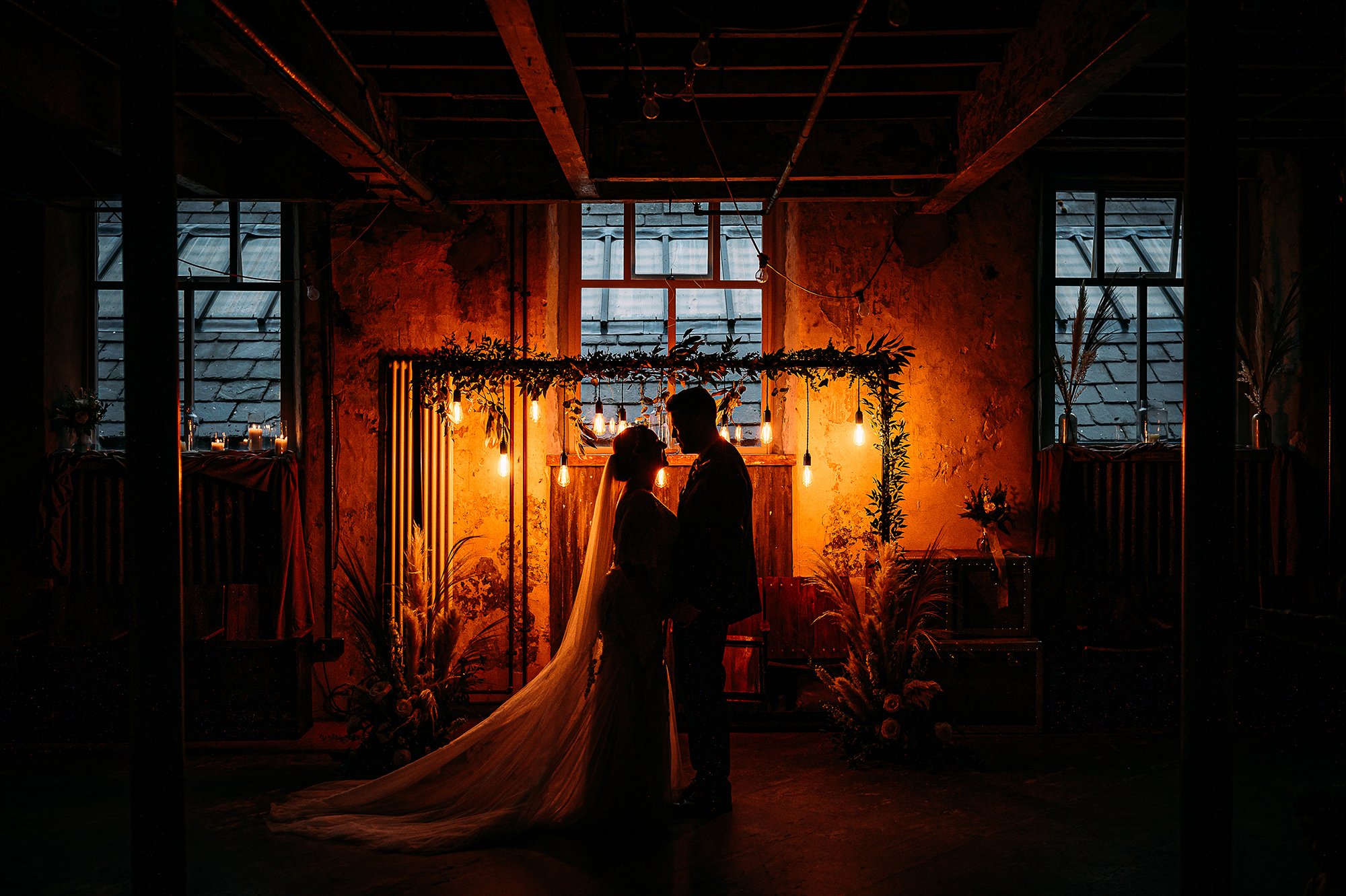  Couple portrait at Holmes mill with orange lights on the walls. 