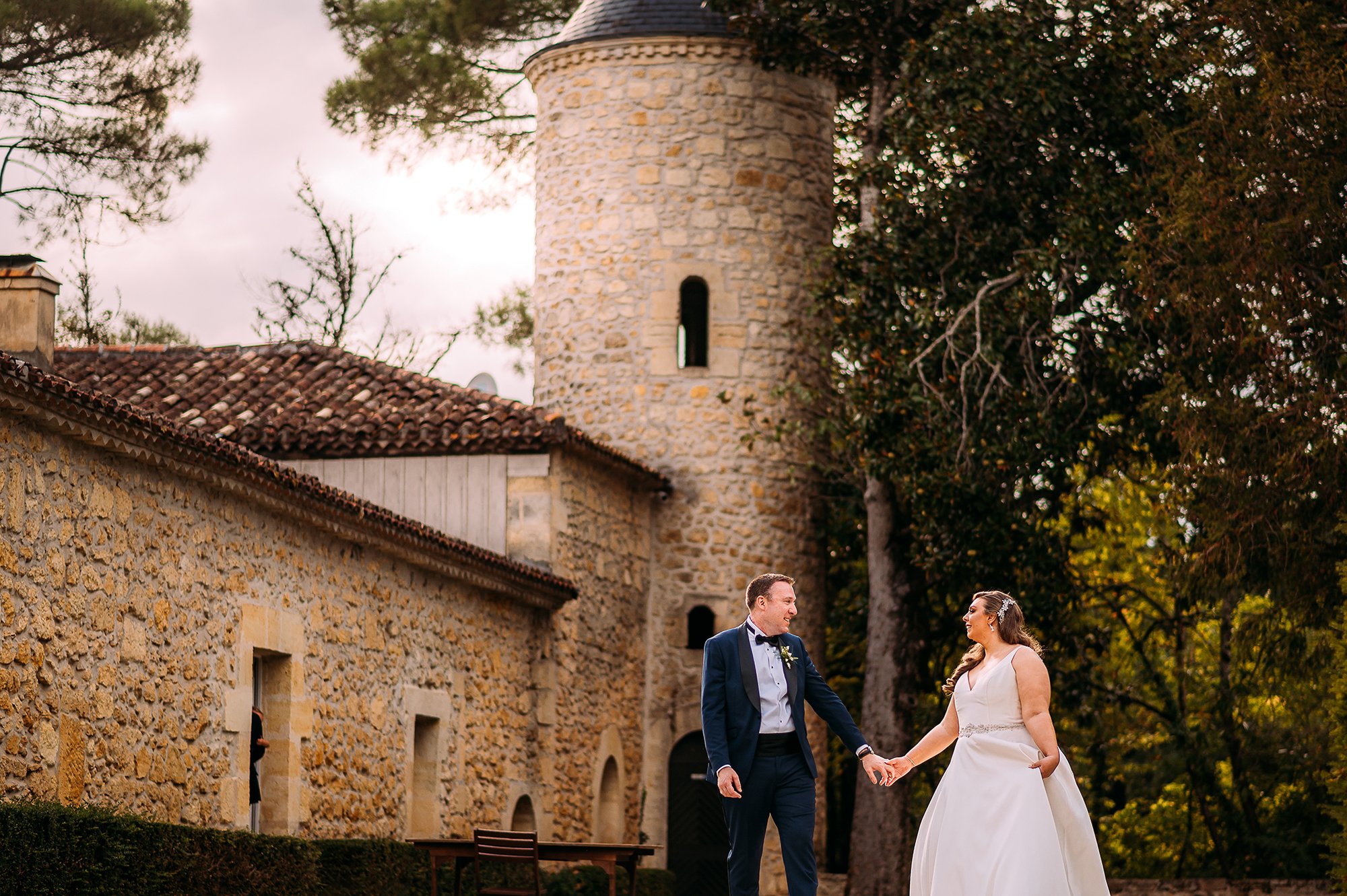  Couple walking in front of chateau wedding venue. 
