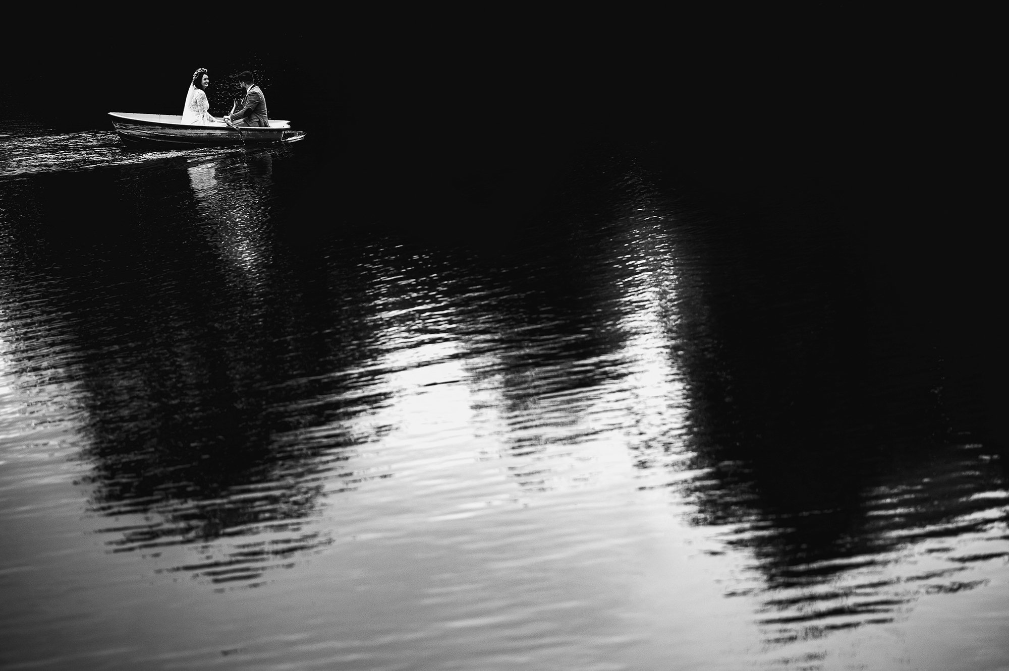  Bride and groom rowing a boat on a lake. 