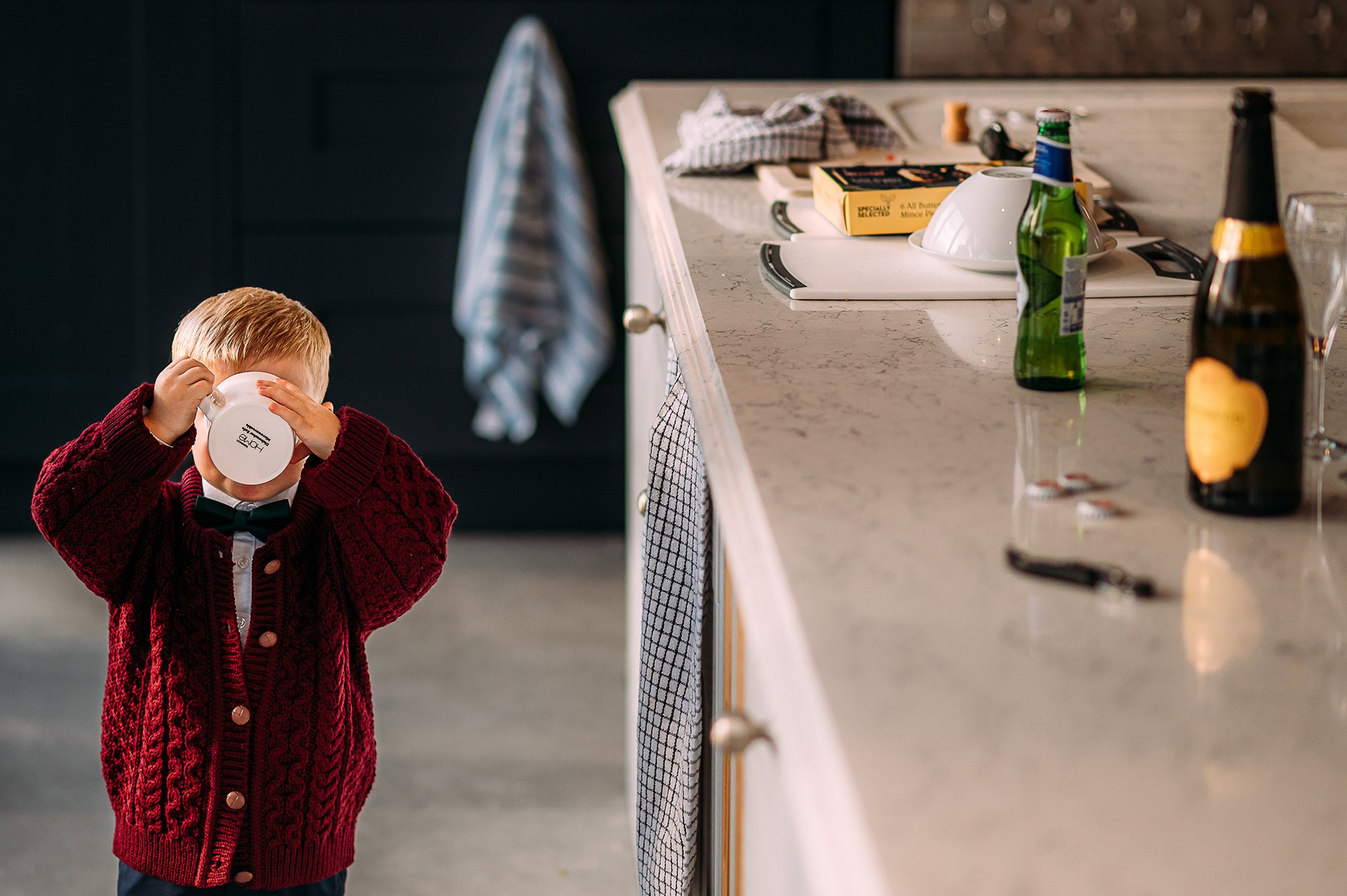  Boy covering his face as he drinks from a cup. 