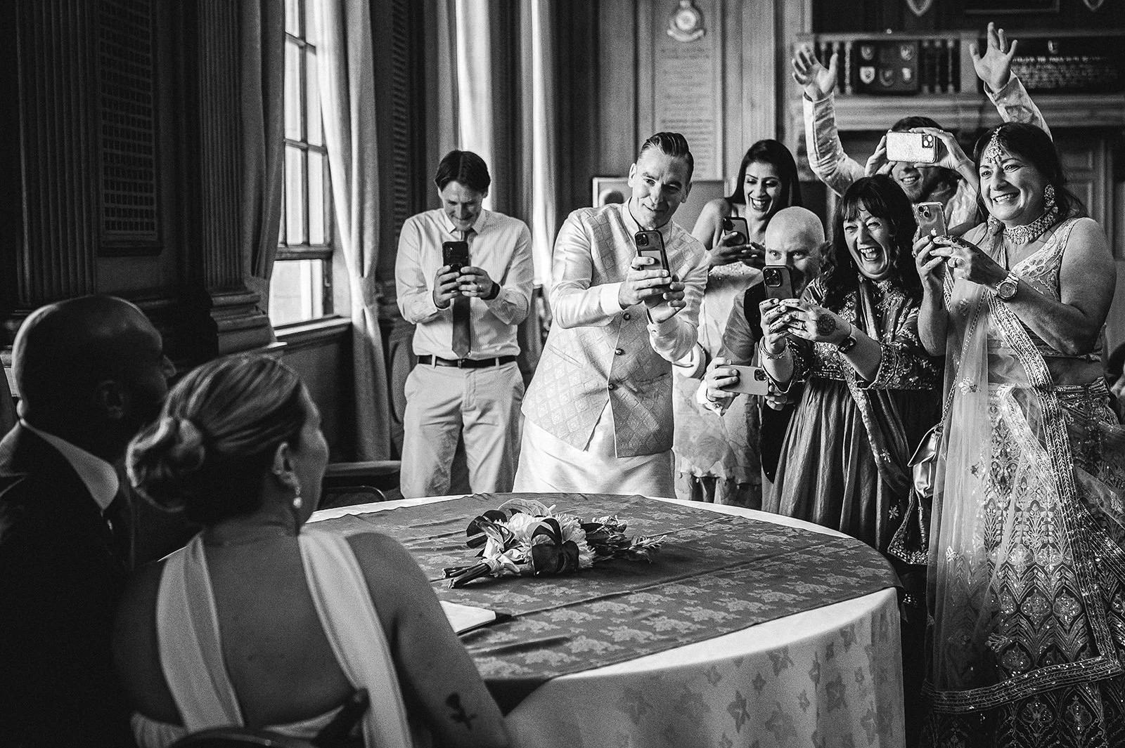  Guests taking pictures of newly married couple as they sign the register 