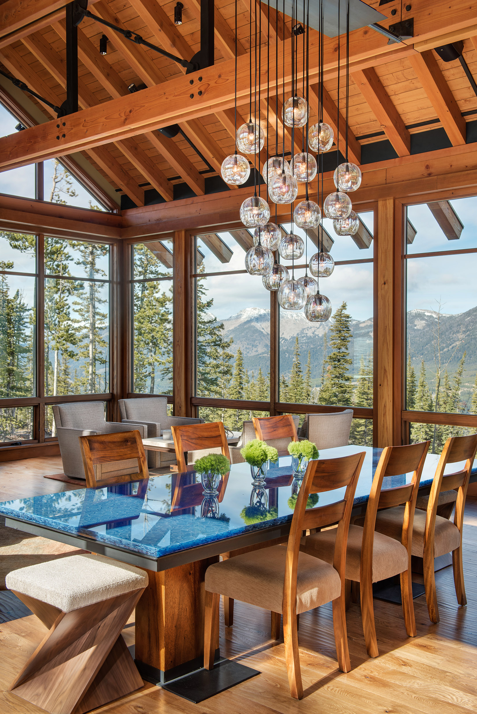 Everything about this dining room I love - the big windows to capture the views, the blue table, and those hanging lights!! Varda Interiors