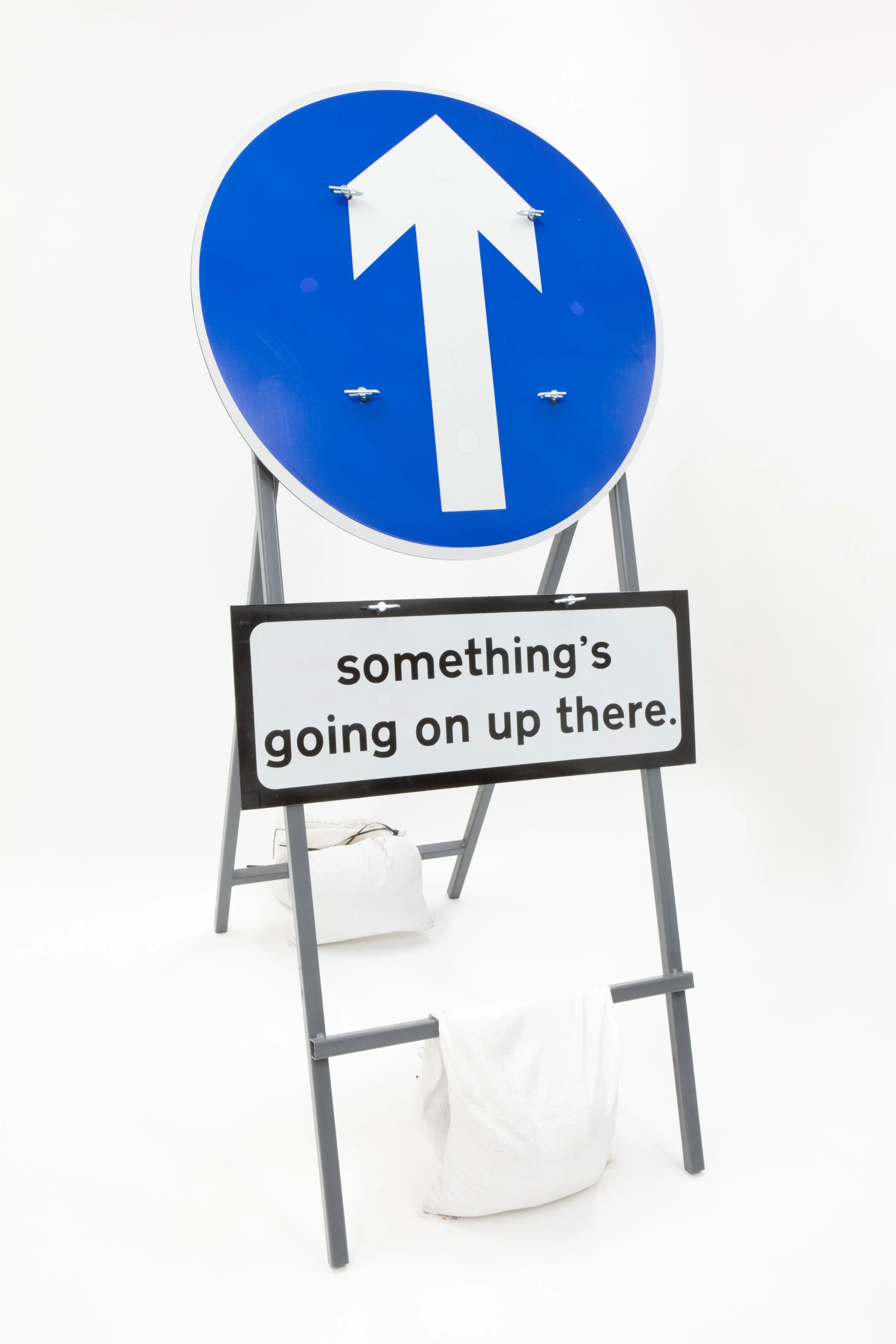  something’s going on up there  road signs and sand bags on steel stand  62” x 28.5” × 38” 