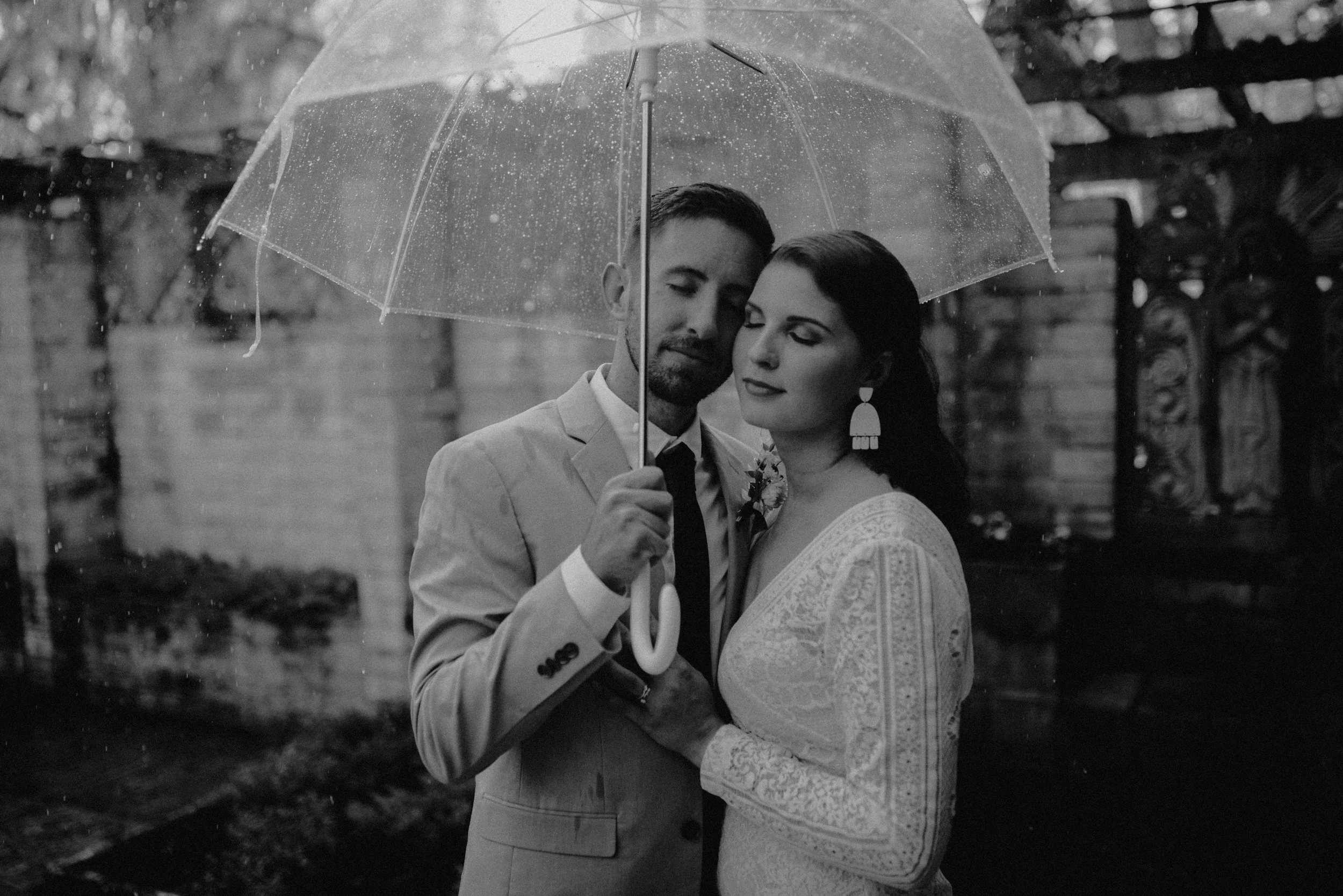 married couple under clear umbrella in rain intimate moment