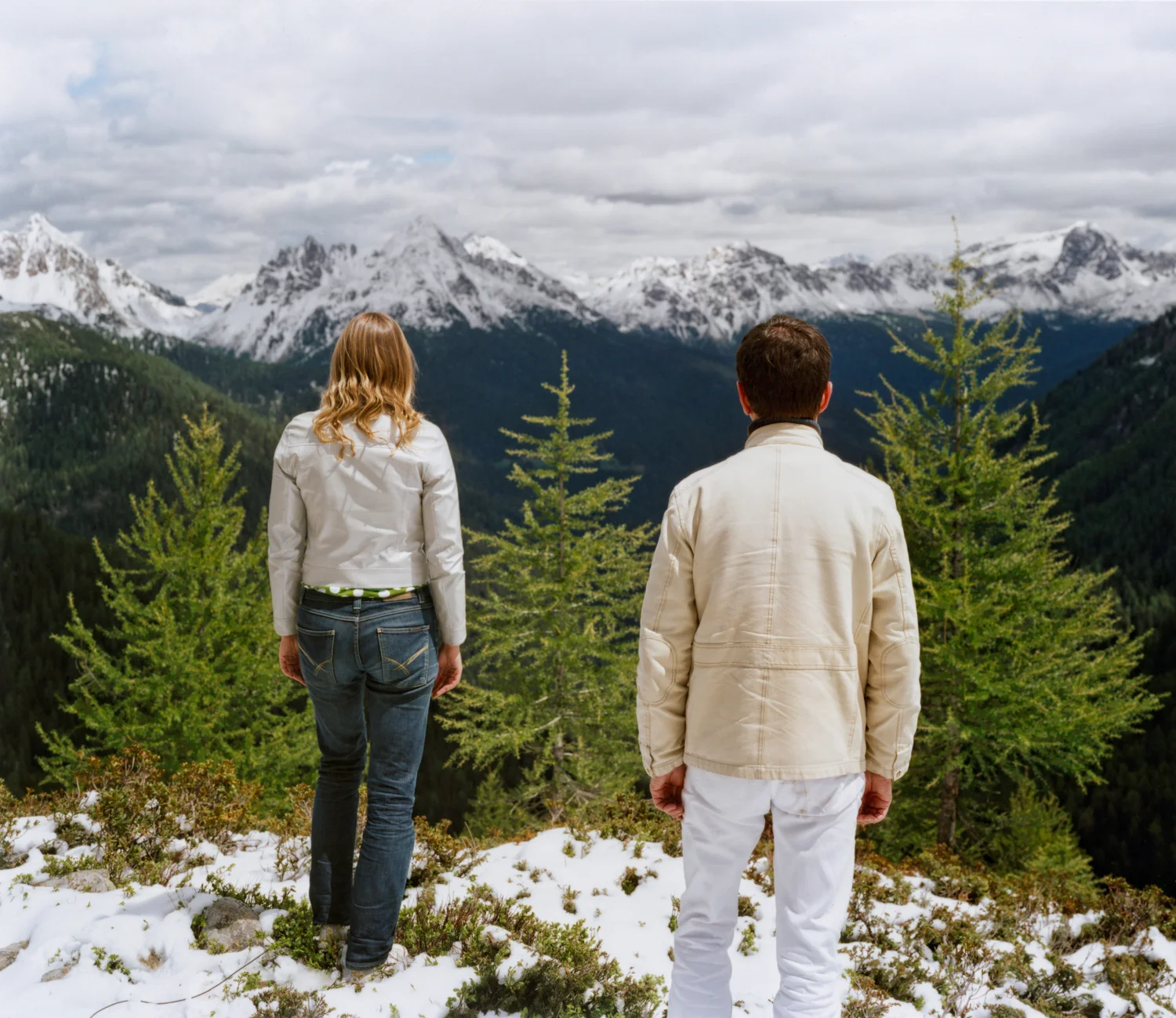Two figures in front of a mountain landscape