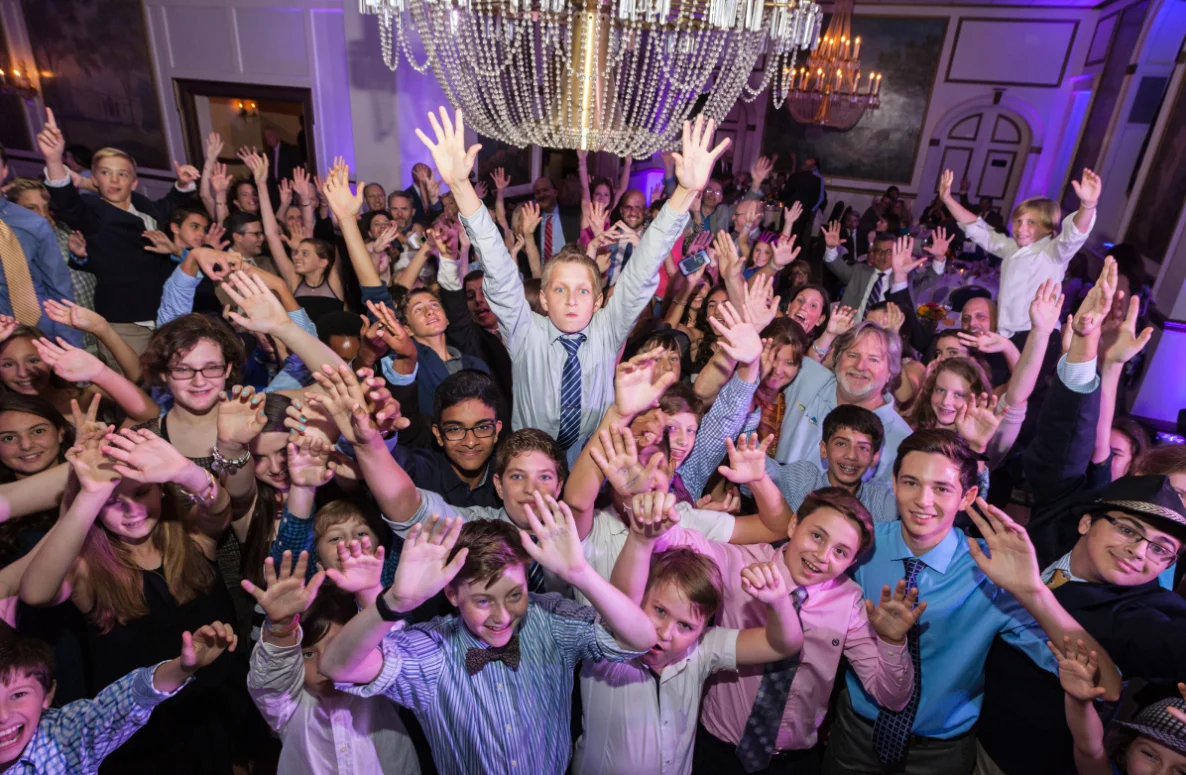 A large group of elementary school students cheering and dancing at a school event in Rochester, NY, hosted by Sound Express Entertainment.