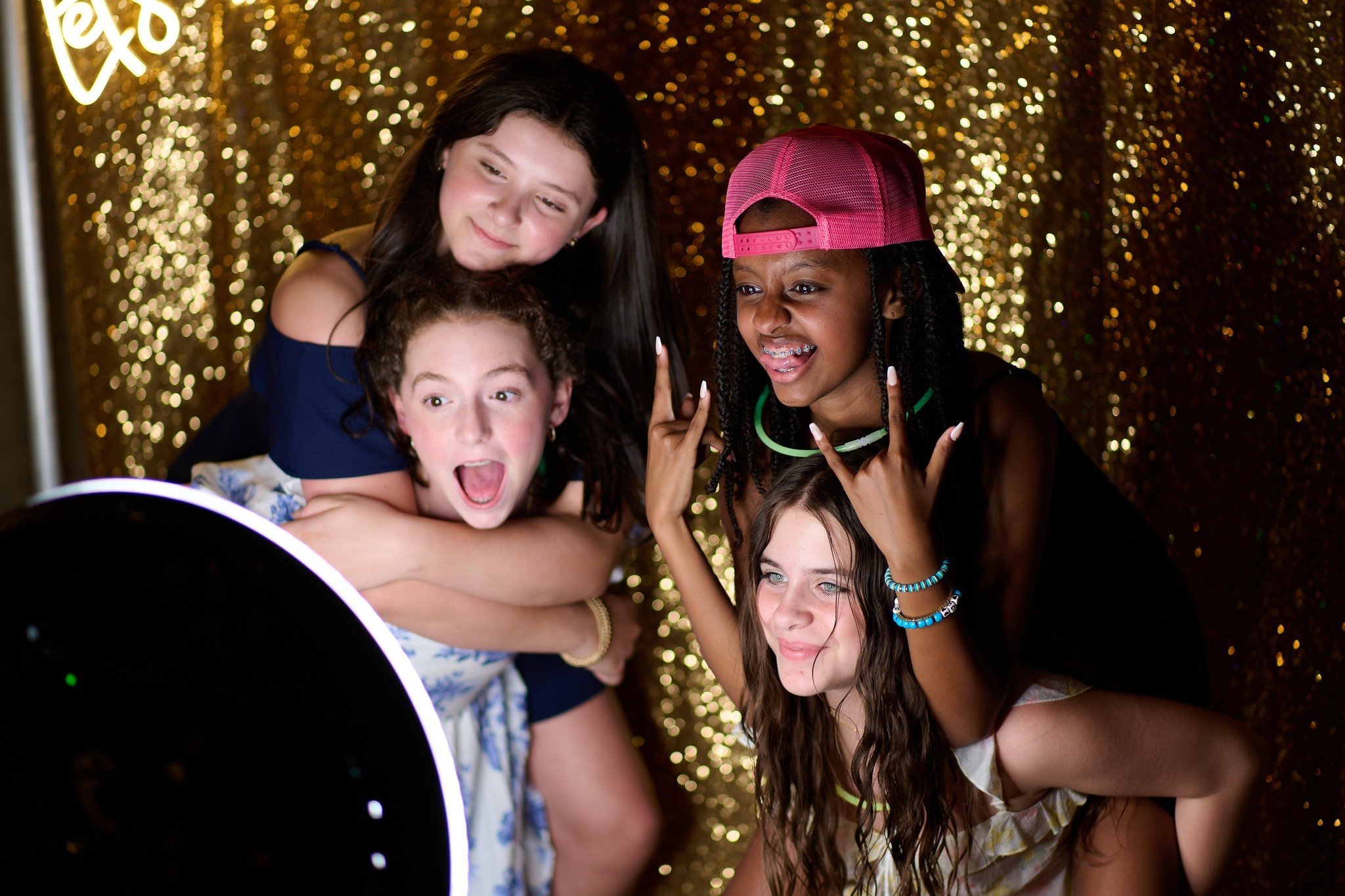 Guests smiling and using an interactive touchscreen photo booth with custom props at a wedding.
