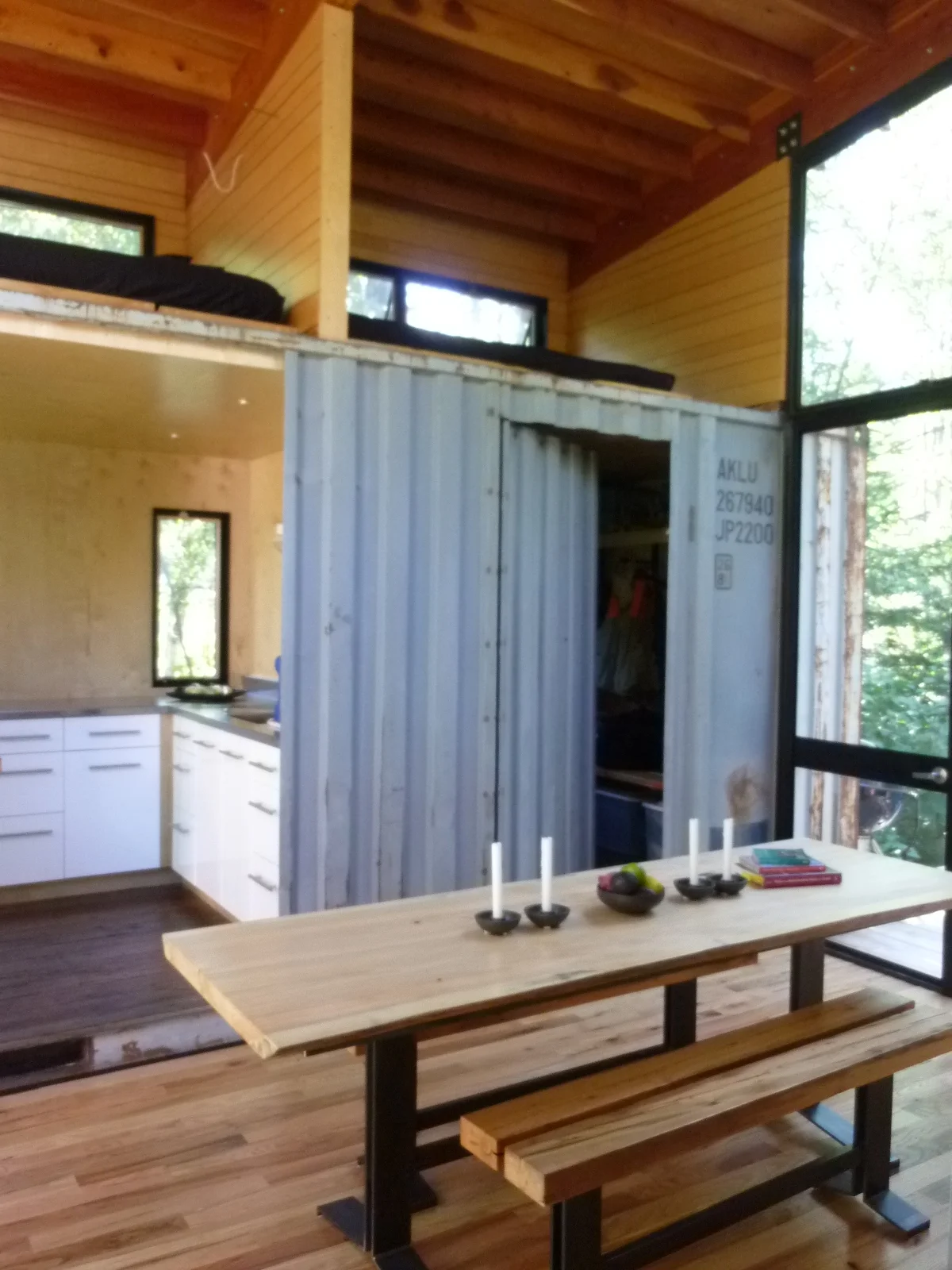  Dining space with sleeping lofts above the blue container. &nbsp;Table frame, benches and top by Innate Works. 