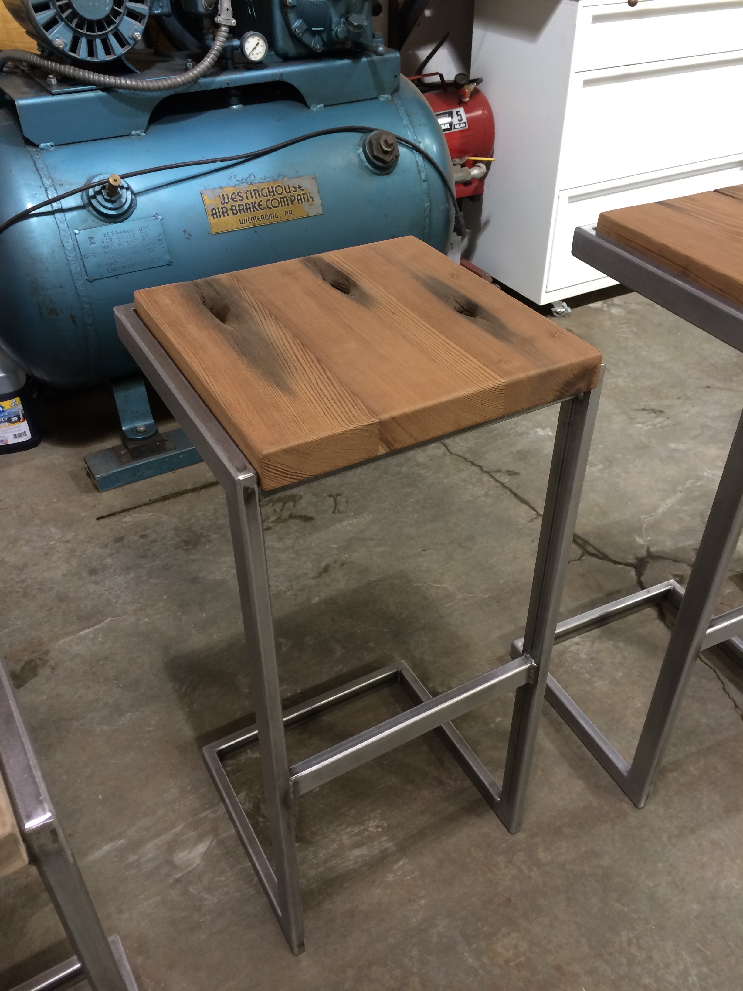  Steel tube and reclaimed redwood. &nbsp;The redwood came from a timber that made up a railroad trestle in Utah. &nbsp;The large holes are from the enormous bolts used to hold the bridge together. &nbsp;The dark streaks are the trace of the rusting b