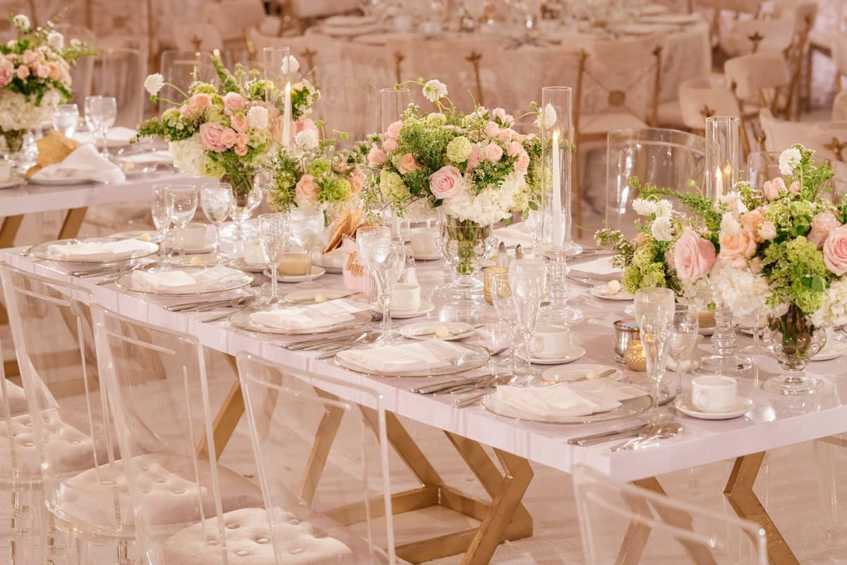 Wedding reception tables with translucent chairs, vases and candle holders, pink and white florals, and copper accents - designed by Eddie Zaratsian, photo by Kris Kan