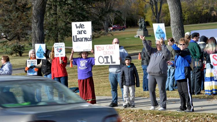 Pipeline protesters hold signs for passing motorists during a rally on the south side of the state Capitol in Bismarck, N.D., on Saturday. (Will Kincaid / The Bismarck Tribune) via LA Times