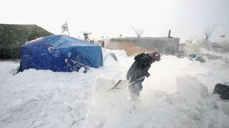 Efrem John, a Dine Navajo from Shiprock, N.M., clears snow from his camp near the Standing Rock Sioux Reservation in North Dakota. (Scott Olson / Getty Images via LA Times)