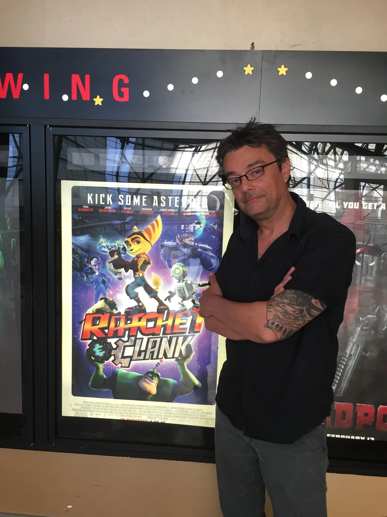 Brian in front of a poster for Rachet and Clank, where he voiced Dallas Wannamaker and Drek Computer.