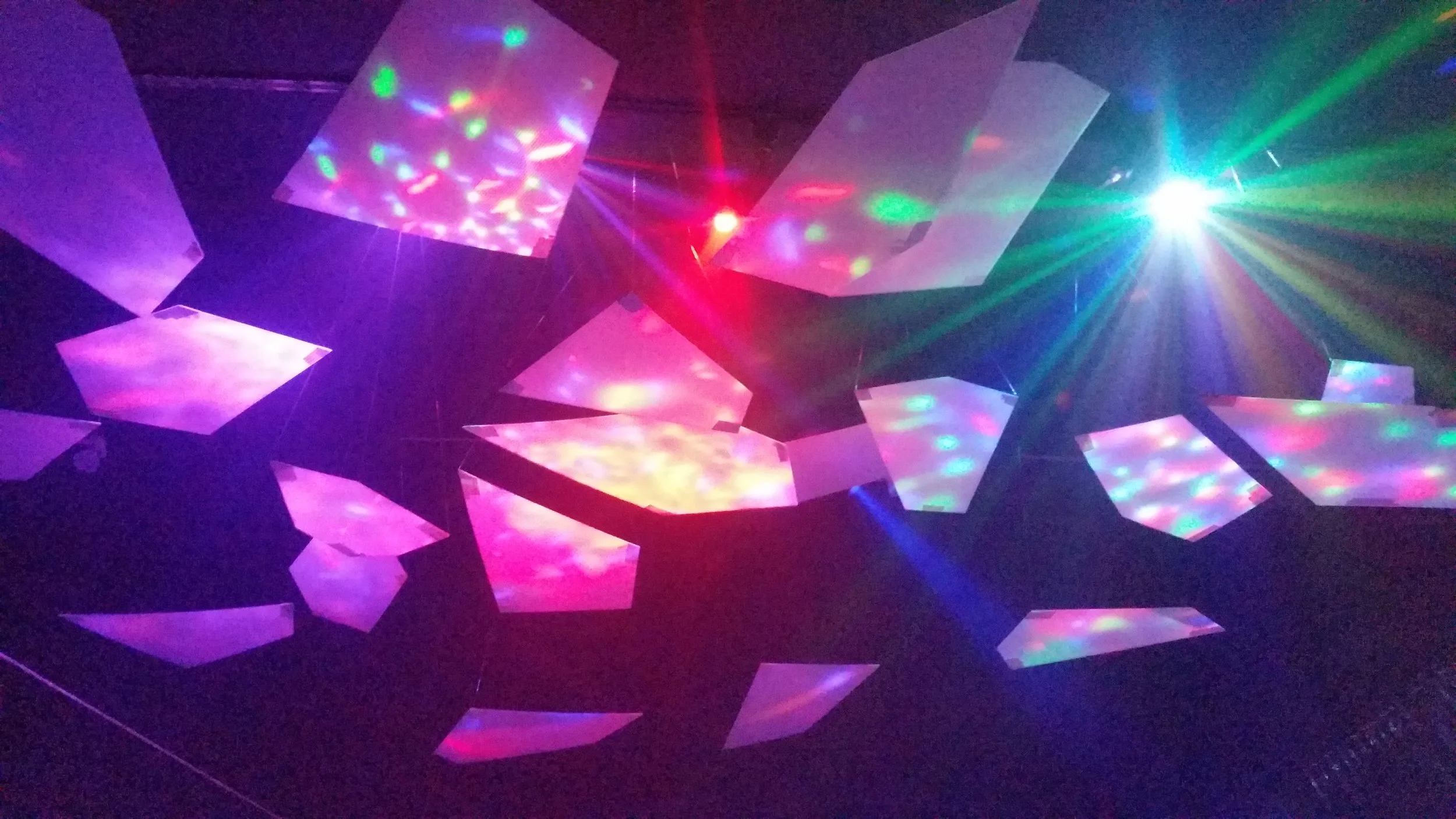 Shattered Cloud by Ryan Phyper Suspended geometric forms made from recycled corrugated plastic sheets, rigged with light weight battery powered LED string lights that created a cascade of colour throughout the space. 