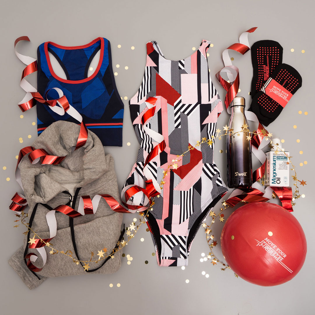 LGBTQ pride-themed assortment including a tank top, swimsuit, socks, hoodie, water bottle, medicine, balloon, and confetti with red and white curly ribbons.