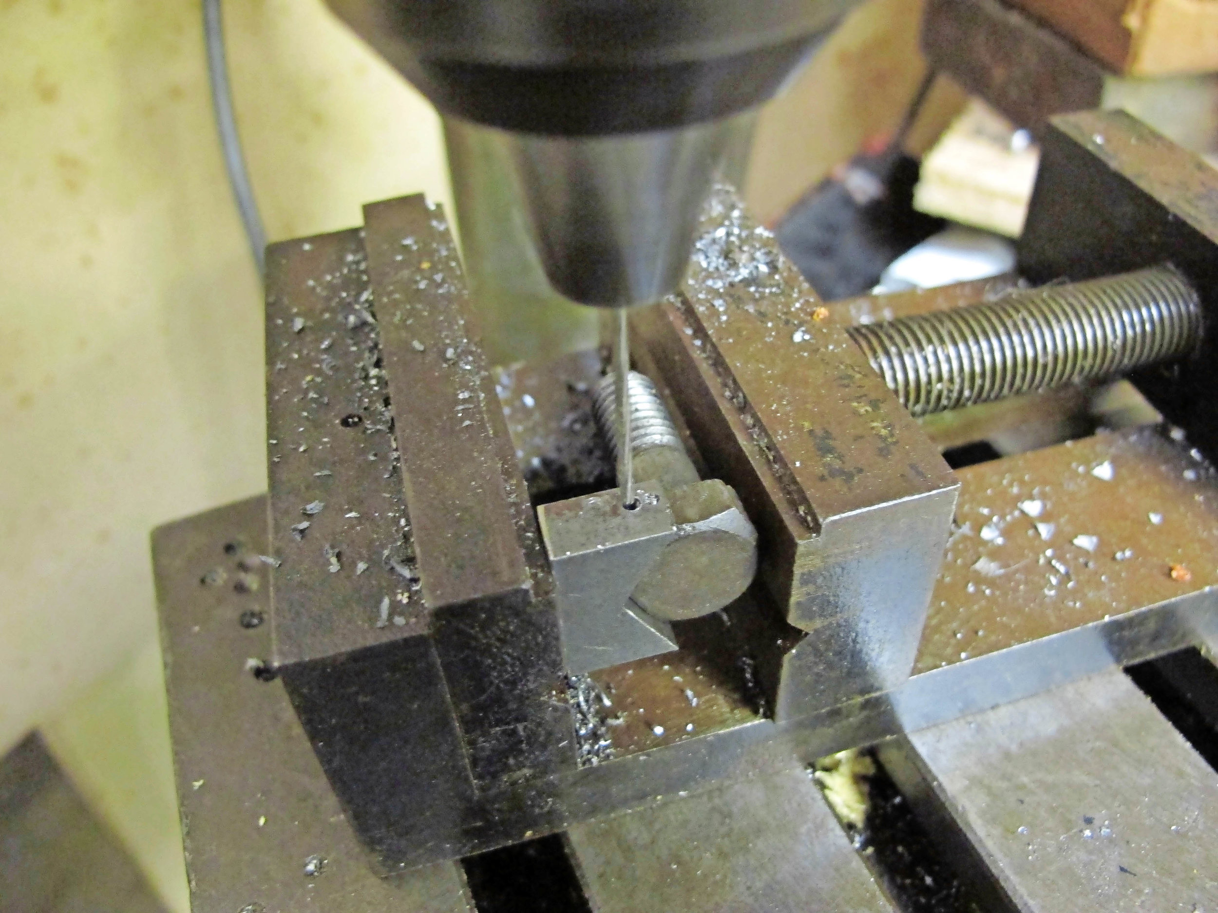4. With the bolt-head located into the jig and clamped into a machine vice, the drilled hole guides the fine bit neatly through the corner of the hexagon without skidding.