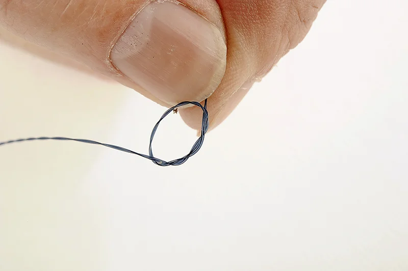 Bring the twisted line back over itself to form an overhand loop knot. Pass the end through itself twice and pull to tighten the knot properly.