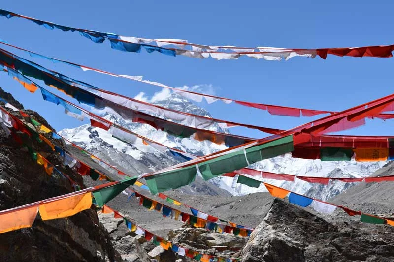 Everest summit looking through Tibetan prayer flags at the Rhombock Monastery. Image by Jon Gupta
