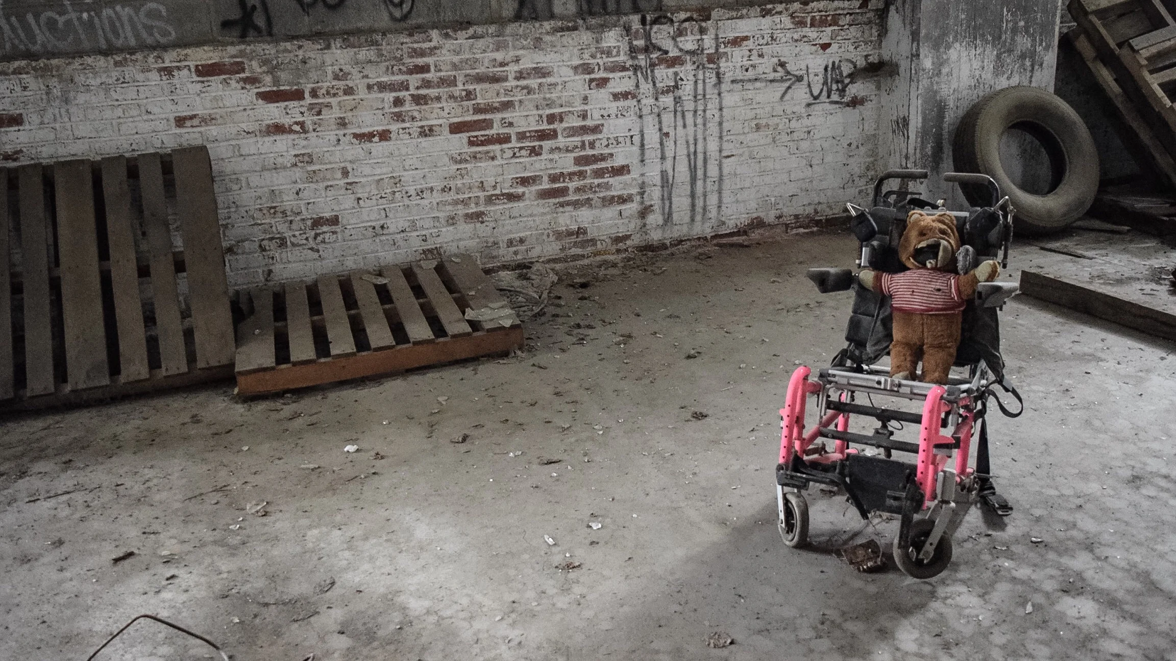 A disfigured teddy bear in a wheel chair. 