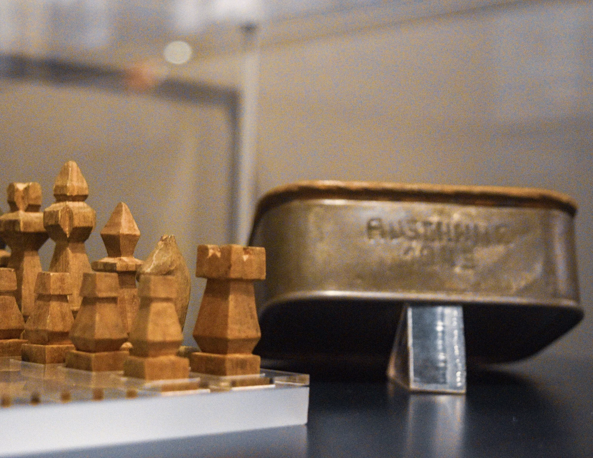 Prisoner handmade chess set and sardine can case, with the word “Auschwitz” carved into it.