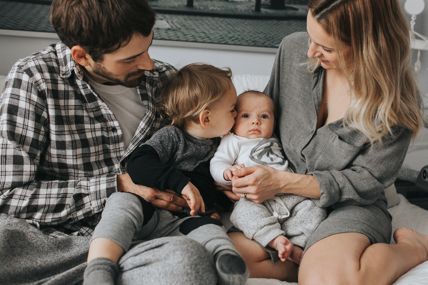 Family of 4 on bed - toddler boy kissing baby brother {Toronto Family Photographer}