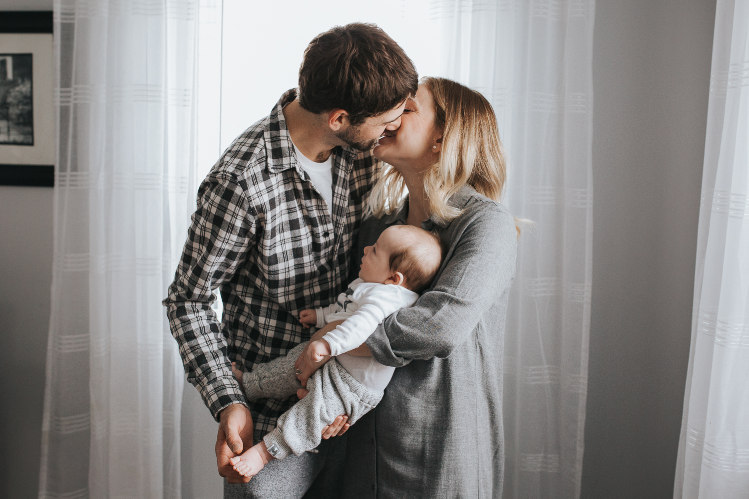 husband and wife kissing holding baby {Toronto Family Photographer}