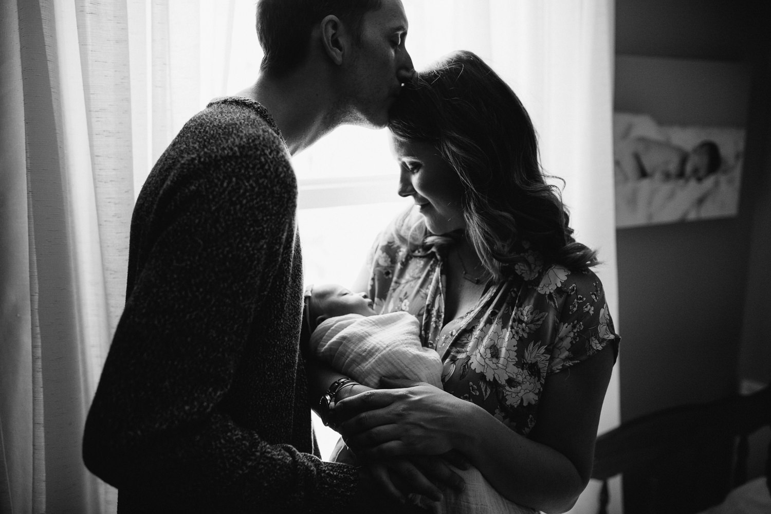 mom holding newborn baby girl while dad kisses mom on forehead - Stouffville newborn photos