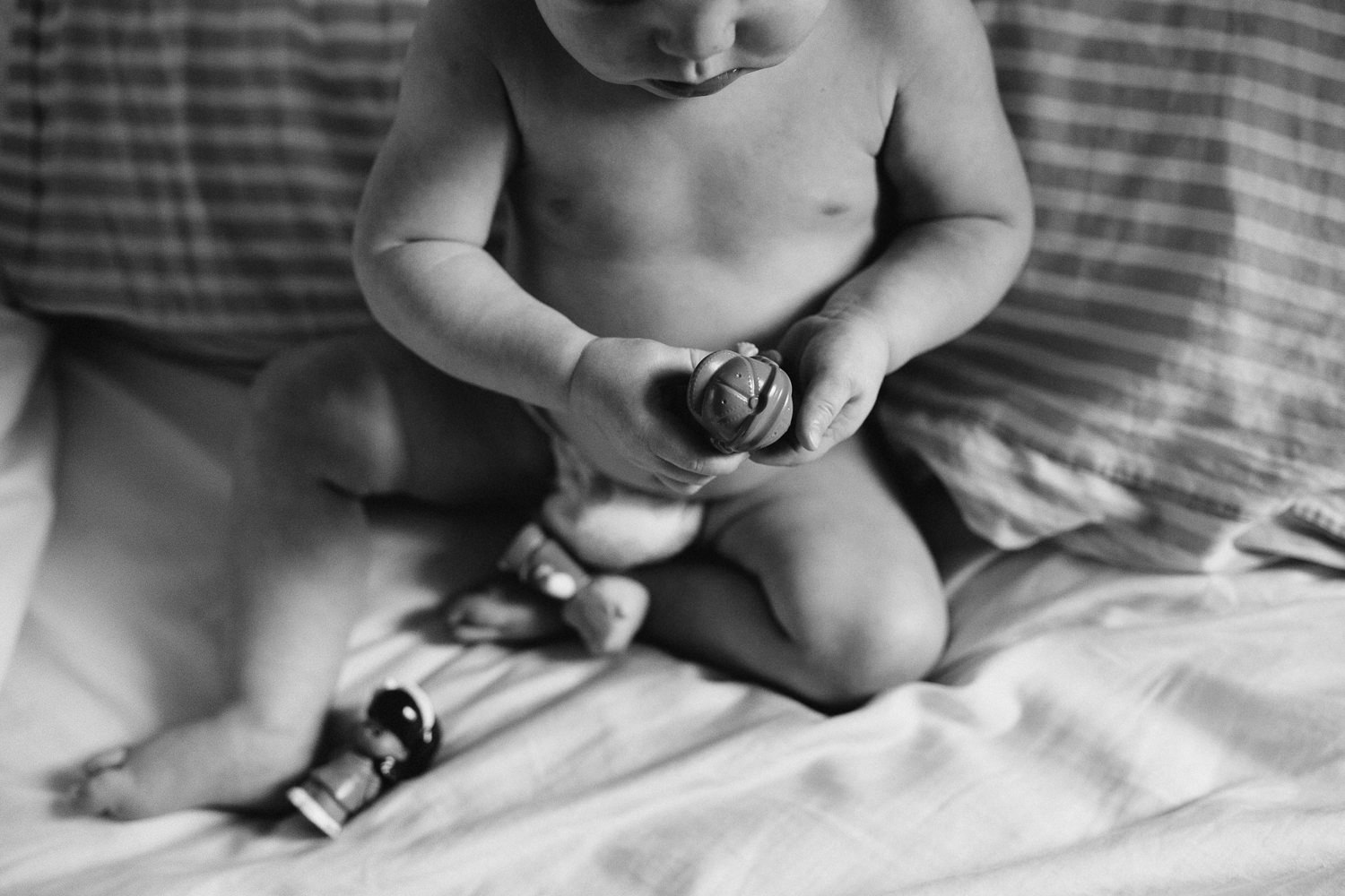 1 year old baby boy playing with toys on bed - Newmarket child photoshoot