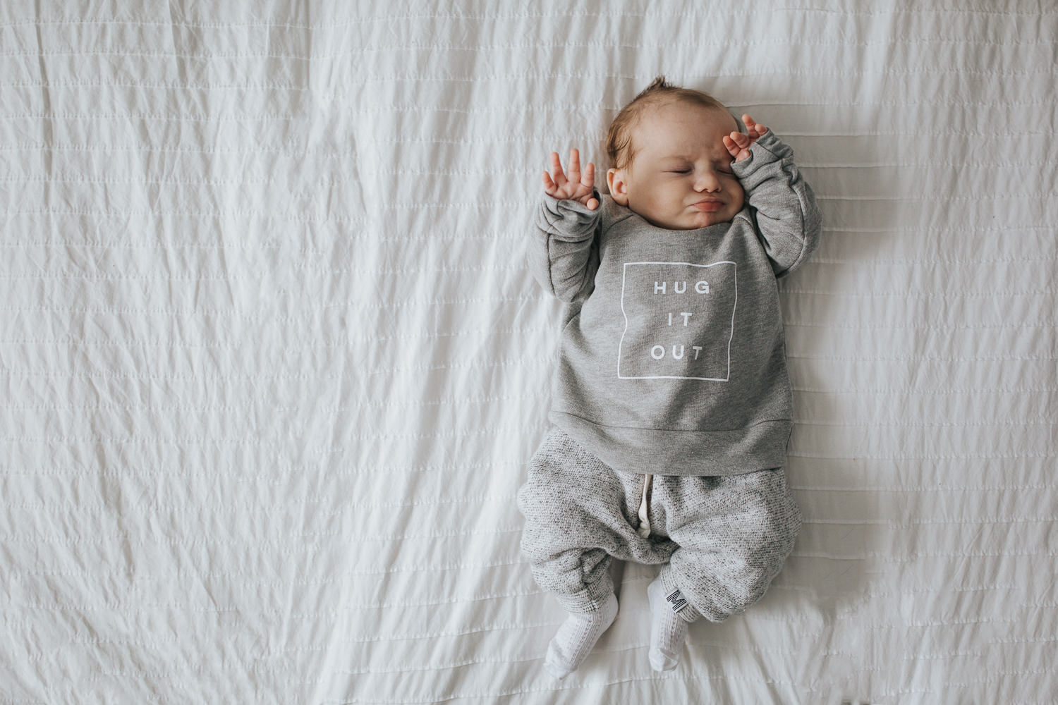 2 month old baby boy rubbing eyes lying on bed - Toronto baby photos