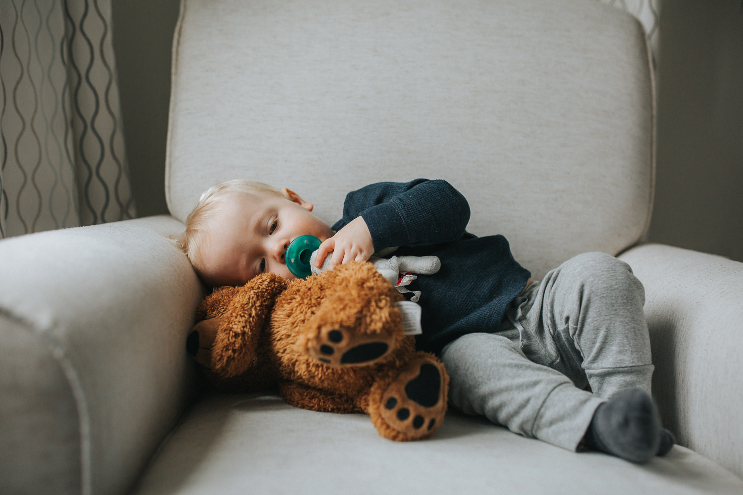 1 year old toddler boy lying on chair with stuffed bear - Newmarket lifestyle photography