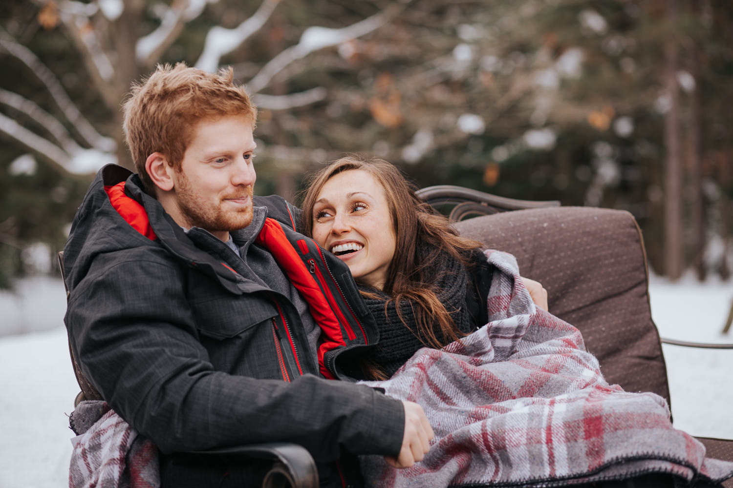 newly engaged couple sitting by fire outside in winter - newmarket lifestyle photos