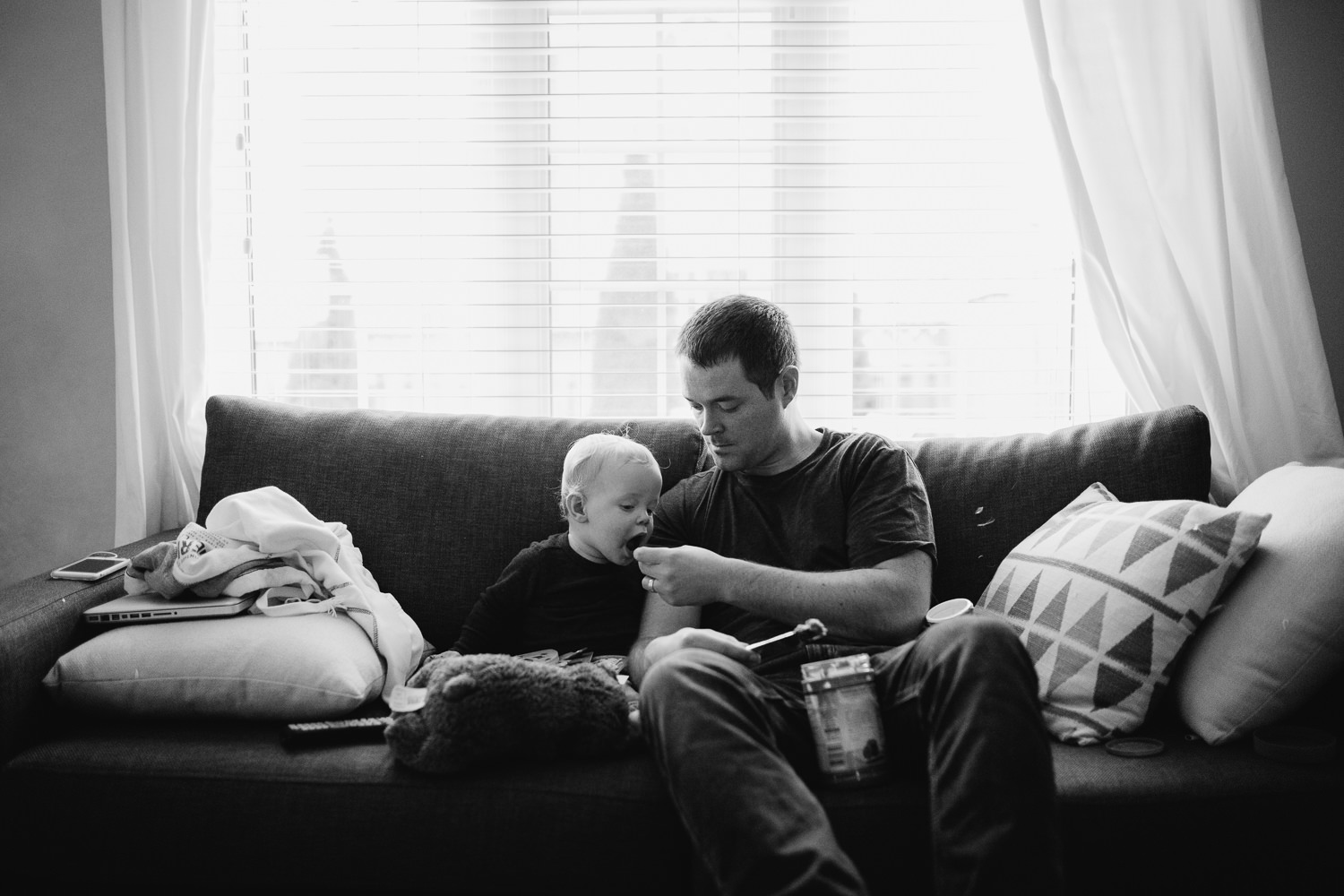 1 year old baby boy eating peanut butter on couch with father - newmarket lifestyle photography