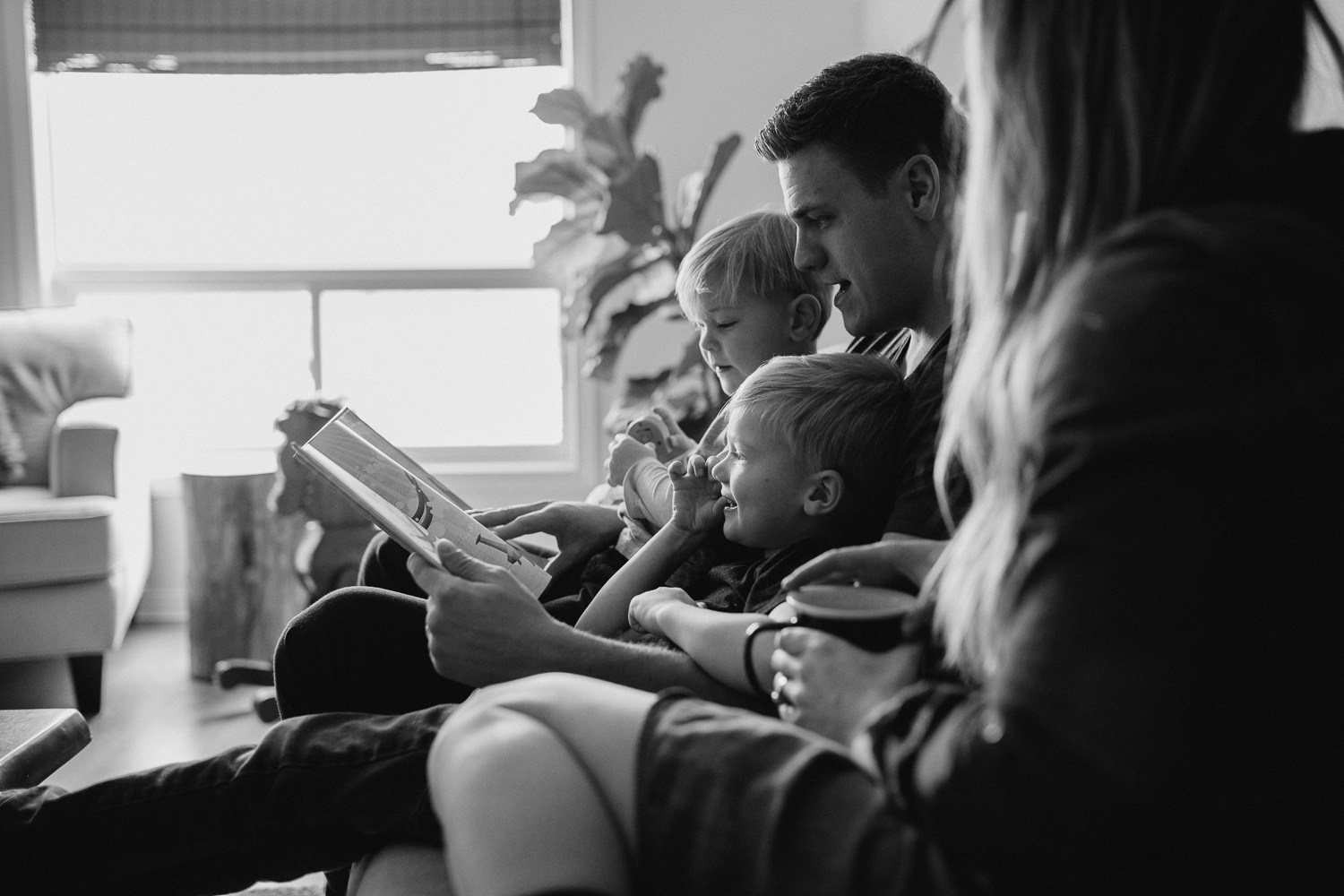 family of four with 2 blonde boys reading book on couch - Markham lifestyle photography