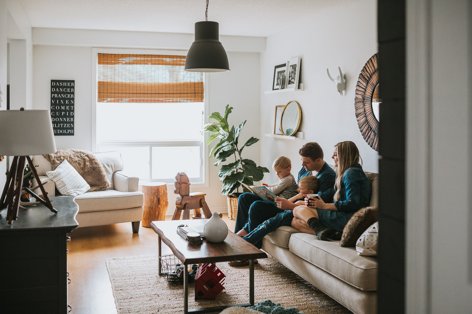family of four with 2 blonde boys reading book on couch - Newmarket Lifestyle Photography