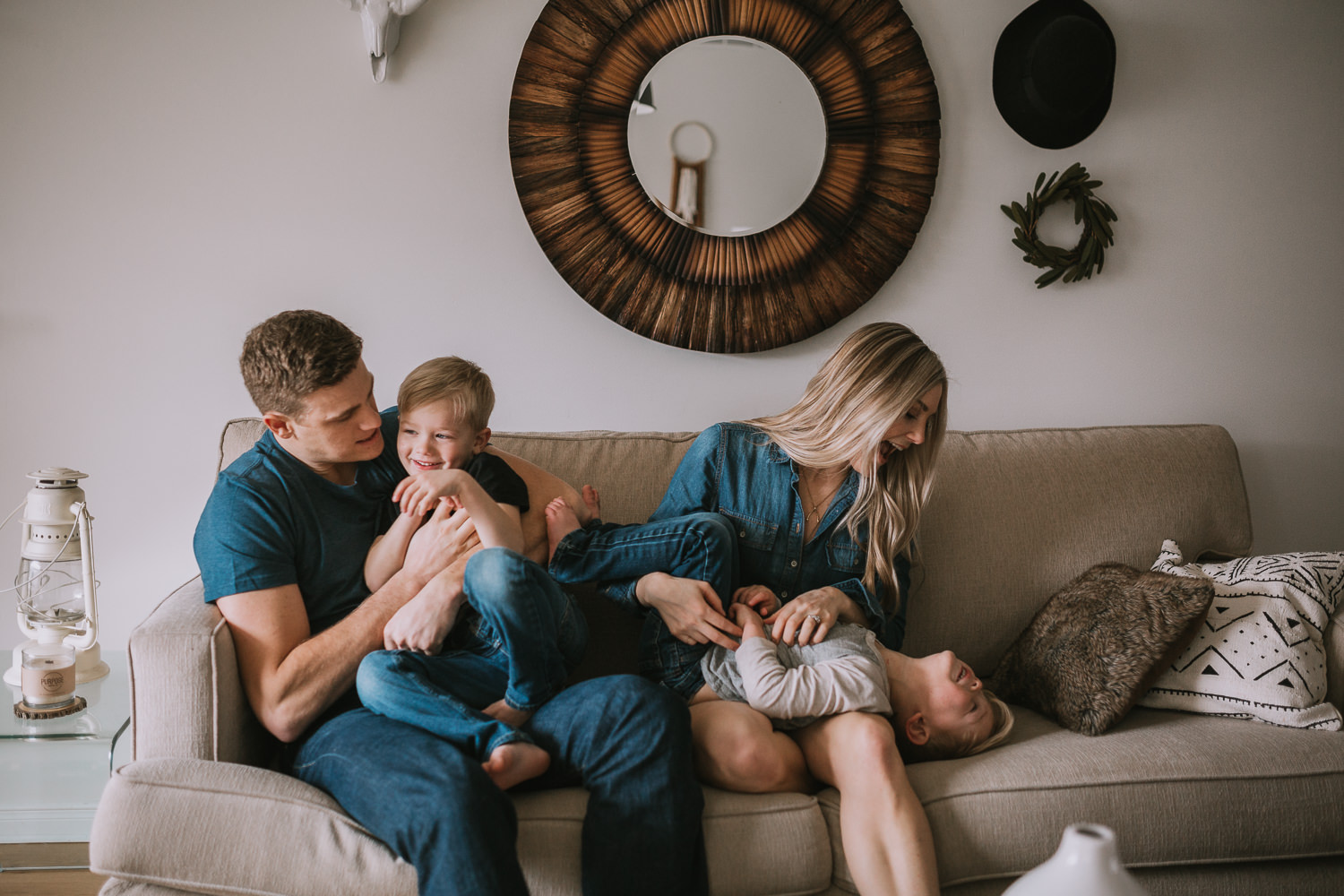 family of four with 2 blonde boys tickling each other on couch - Newmarket lifestyle Photography