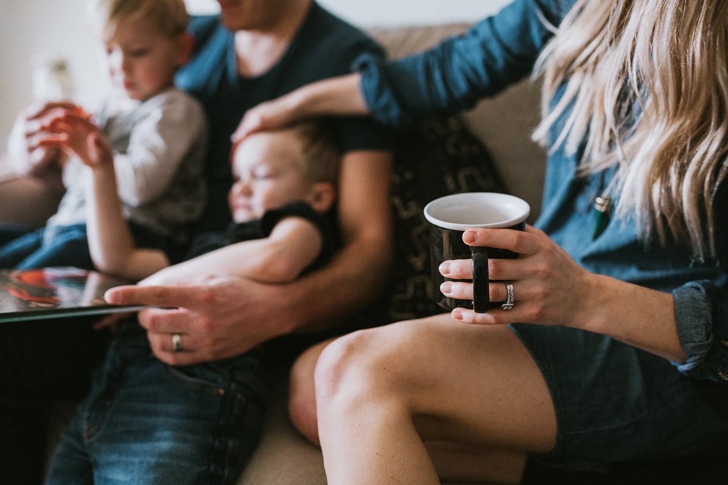 family of four with 2 blonde boys reading book on couch mom holding coffee - Stouffville lifestyle photos