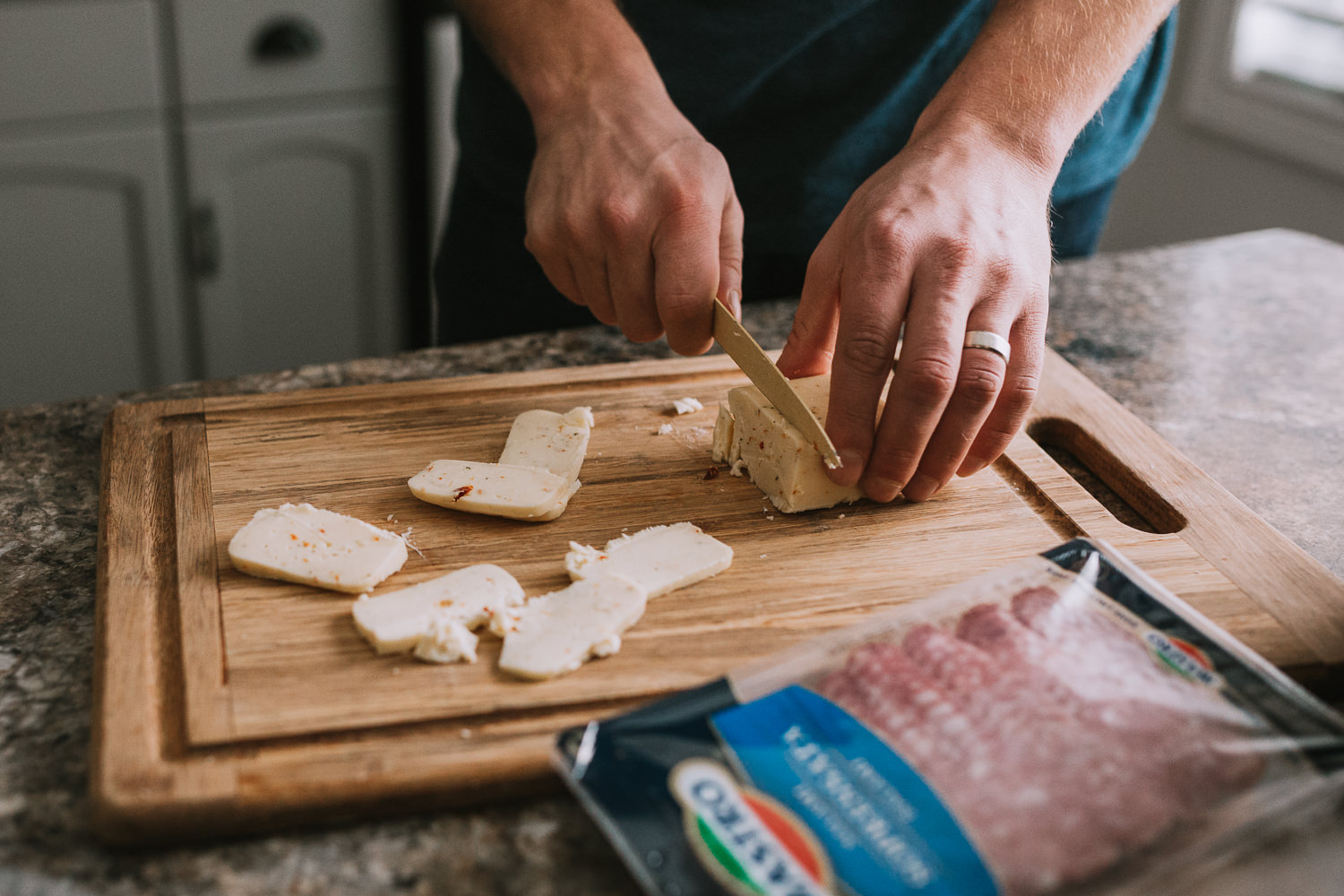 man cutting cheese on wood cutting board - Uxbridge lifestyle photography