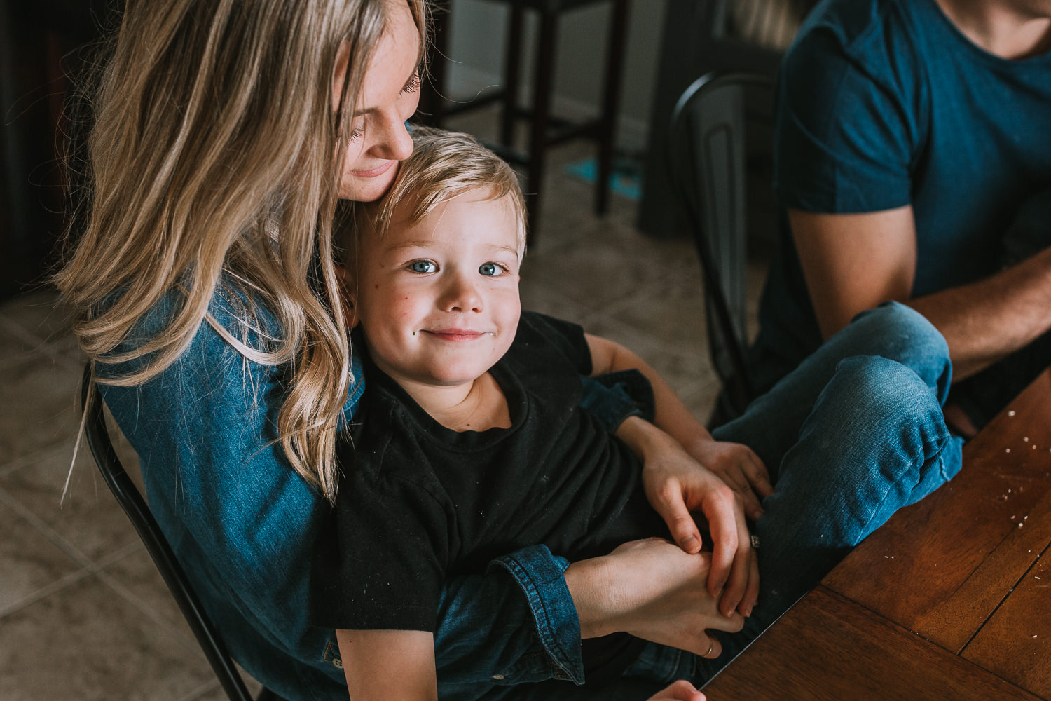 5 year old blonde boy with blue eyes looks at camera while sitting in mother's lap - Stouffville child photos