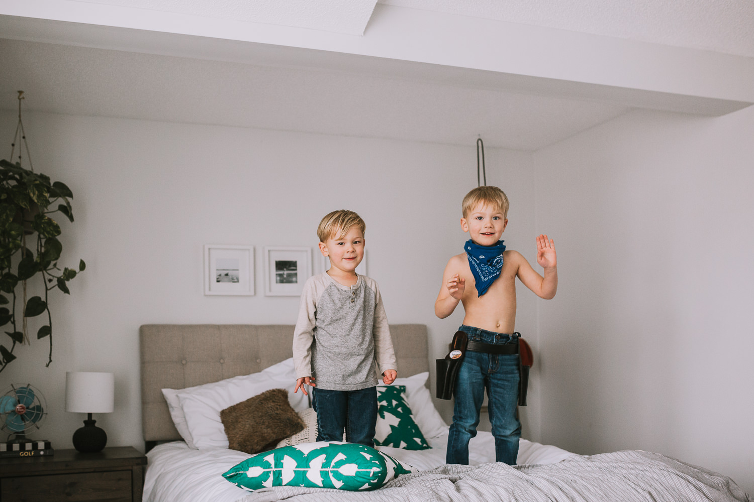 2 young blonde brothers standing on parents bed - Uxbridge lifestyle photography