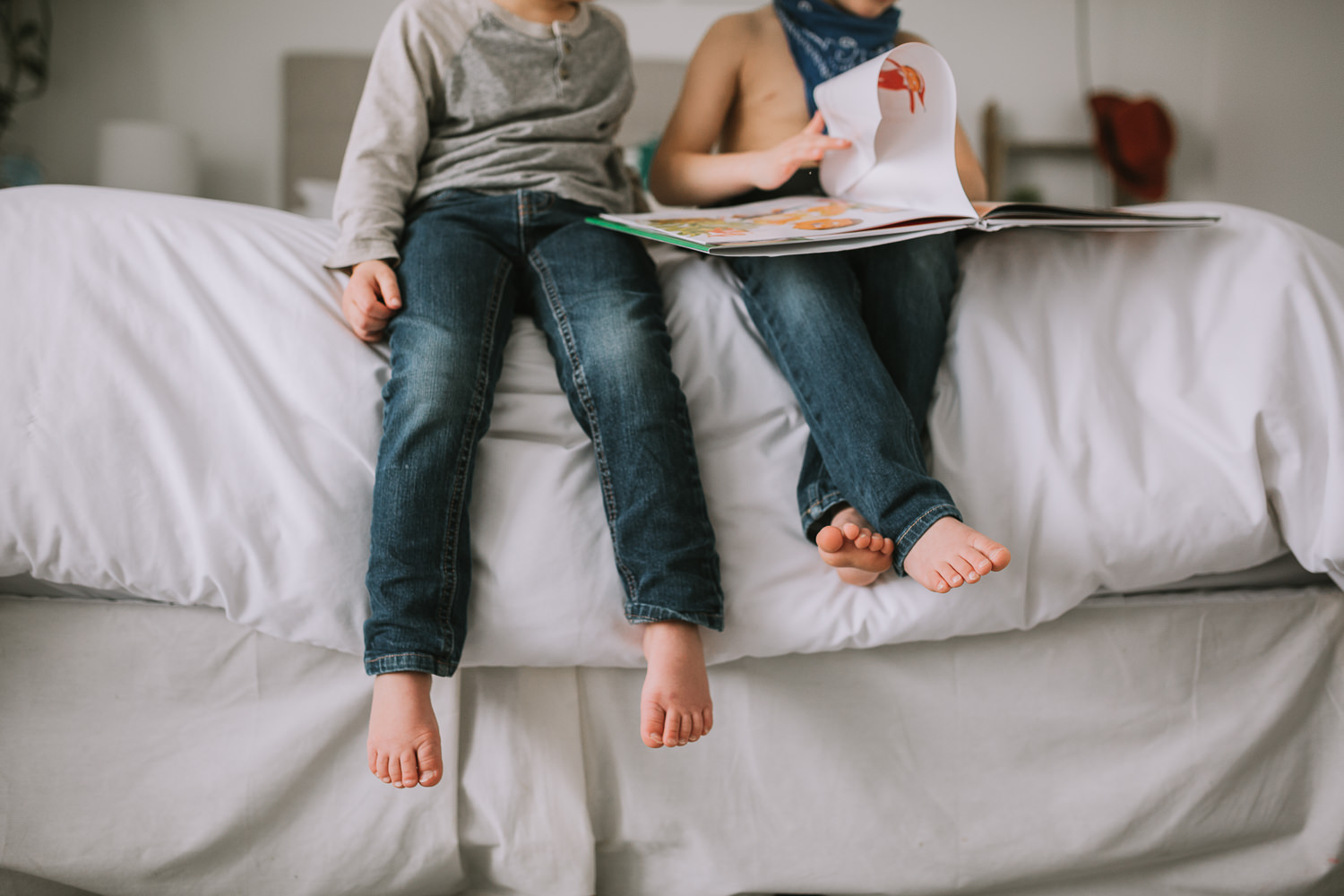 young brothers feet dangle from parents bed as they read story together - Newmarket child photos