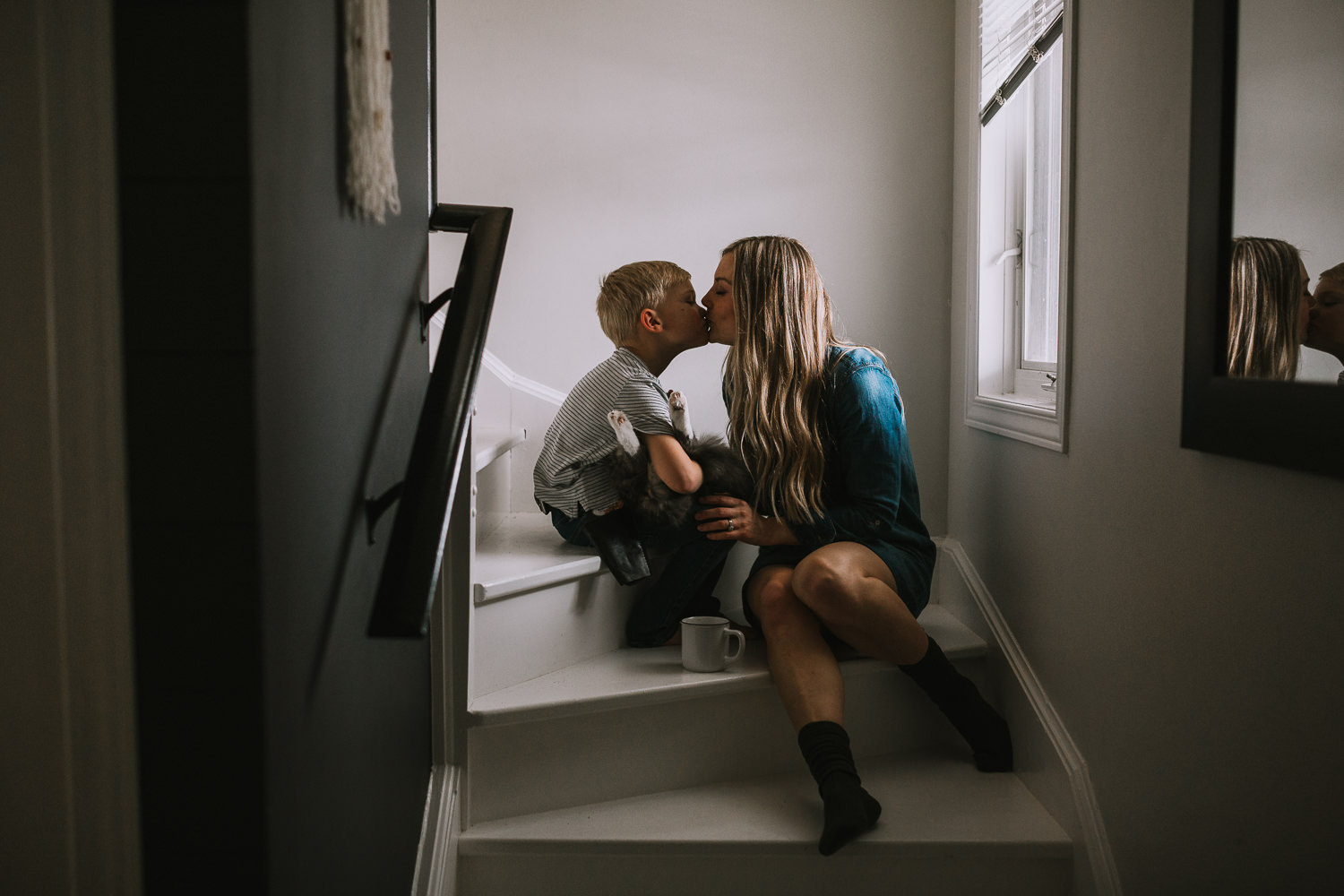 Mom kisses 4 year old blonde son holding pet cat while sitting on stairs - Stouffville child photography