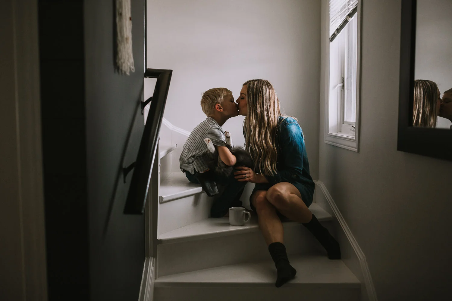 Mom kisses 4 year old blonde son holding pet cat while sitting on stairs - Stouffville child photography