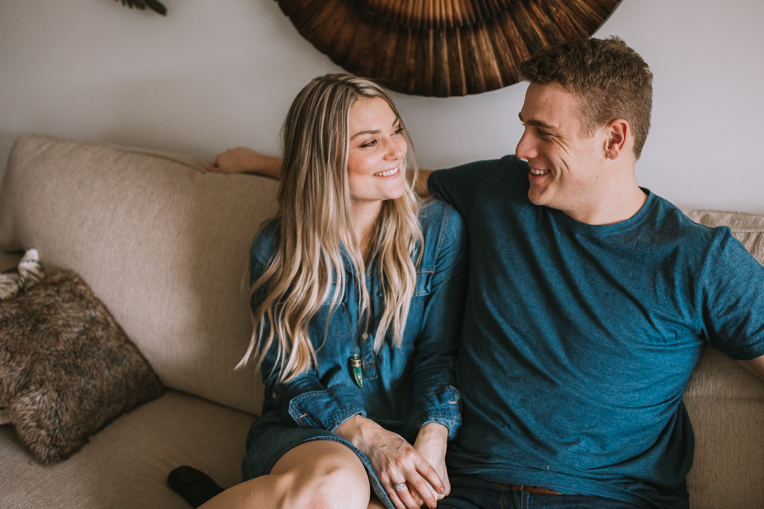 blonde woman with long hair sitting on couch smiling at husband - Newmarket lifestyle photography