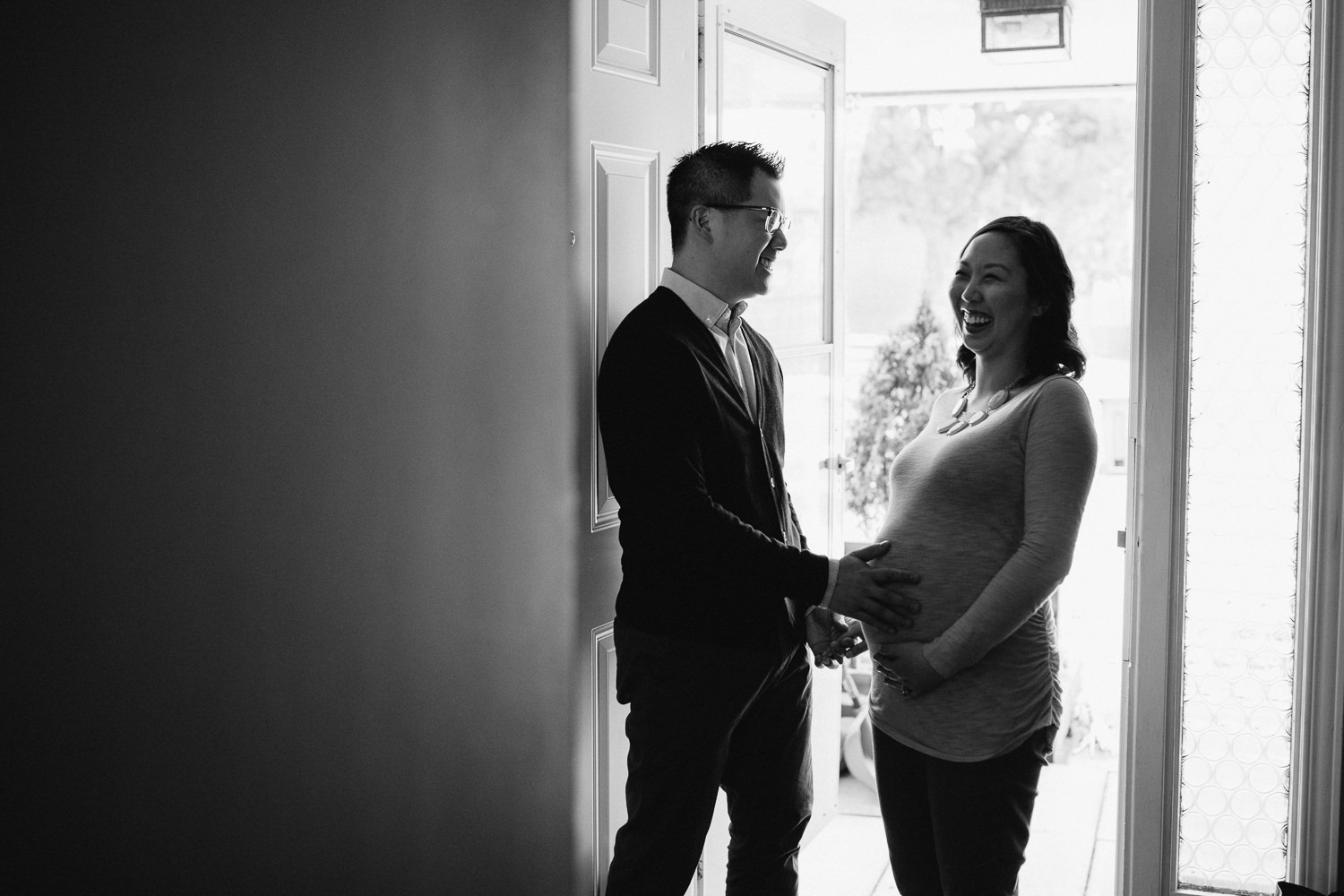 husband and pregnant wife laughing in doorway - Newborn Lifestyle Photography