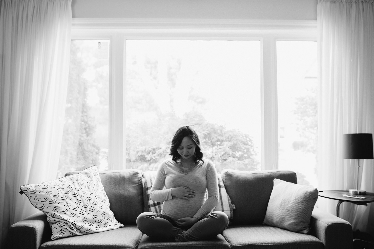 pregnant woman sitting on couch holding baby bump - stouffville in-home photography